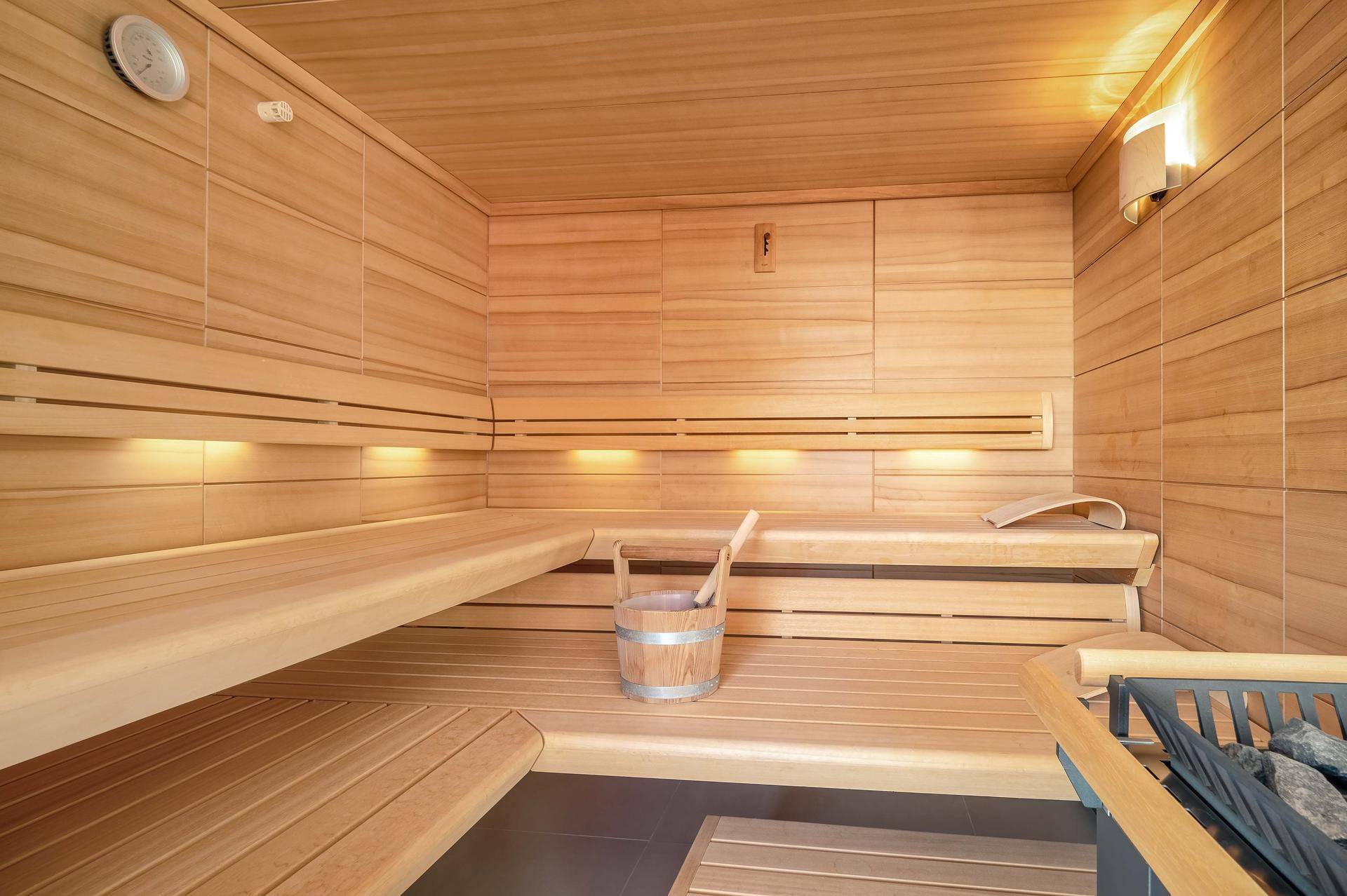 Gemütliche Holzsauna mit mehreren Bänken und traditionellem Saunaofen für entspannende Momente.