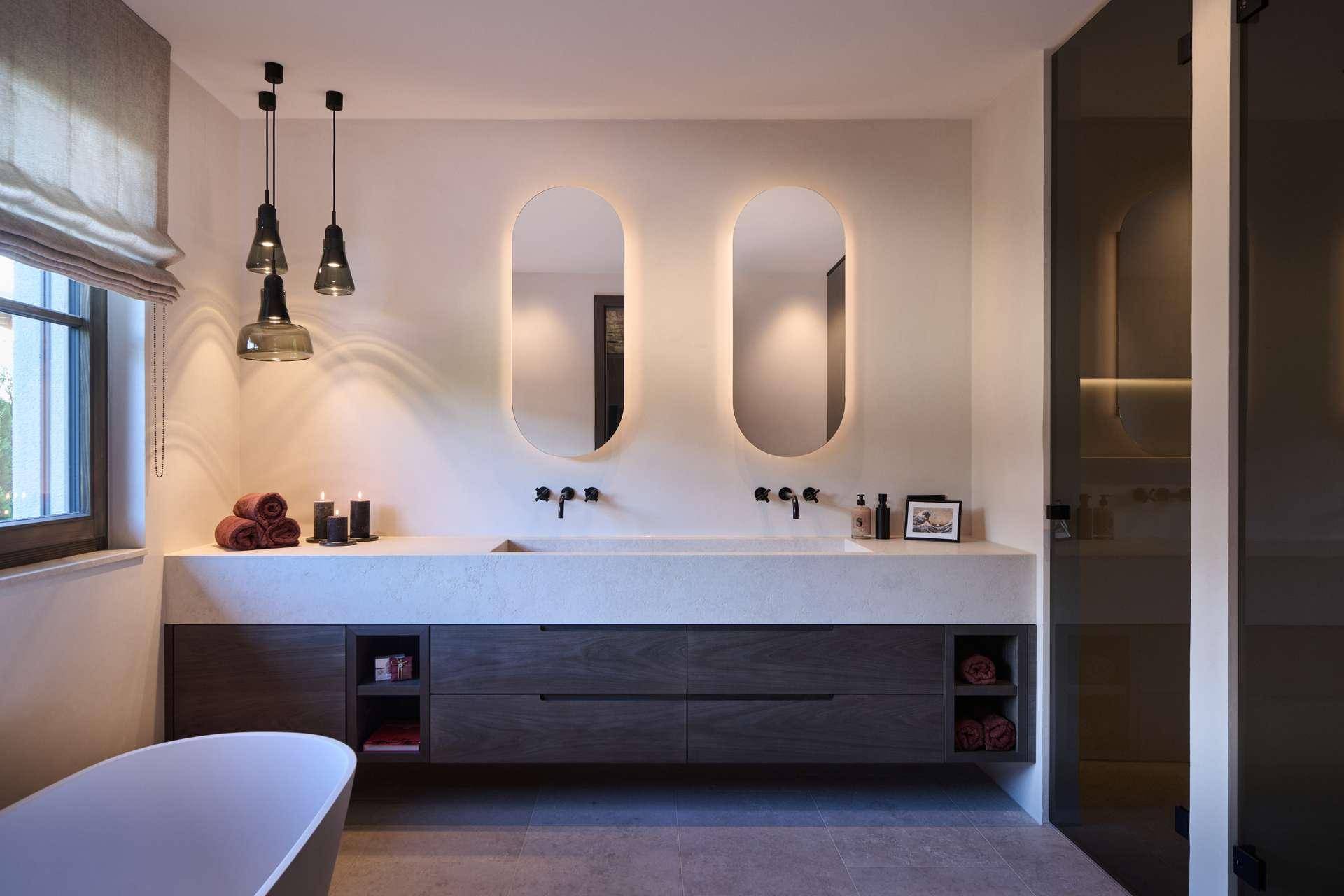 Elegantes Badezimmer mit Doppelwaschbecken, freistehender Badewanne und modernen Spiegelschränken.