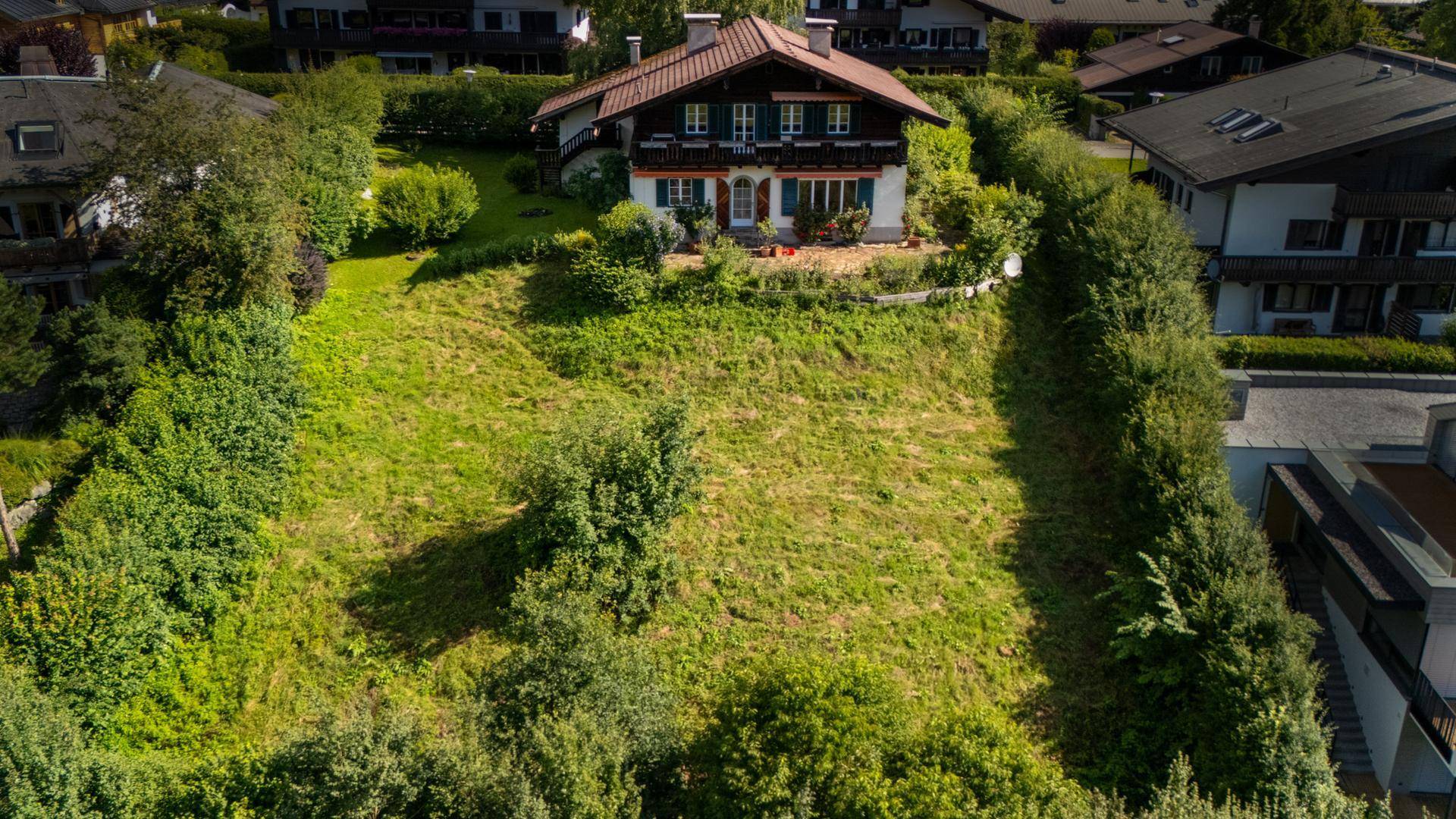 Luftaufnahme eines traditionellen Hauses auf einem Hügel mit großem, grünem Grundstück und Hecken.