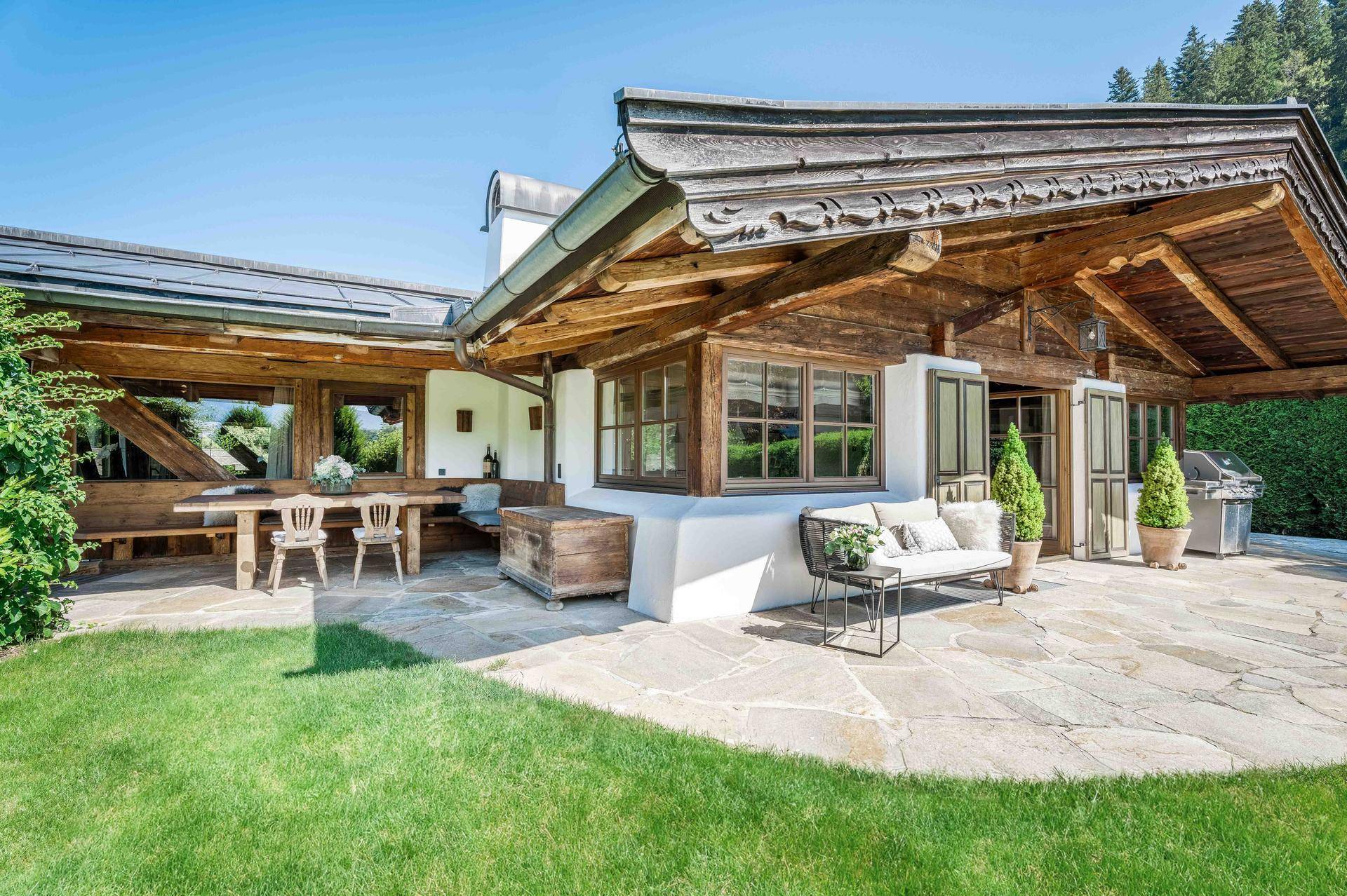 Geräumige Terrasse mit Essbereich und Lounge-Möbeln, umgeben von Grün und traditioneller Holzarchitektur.
