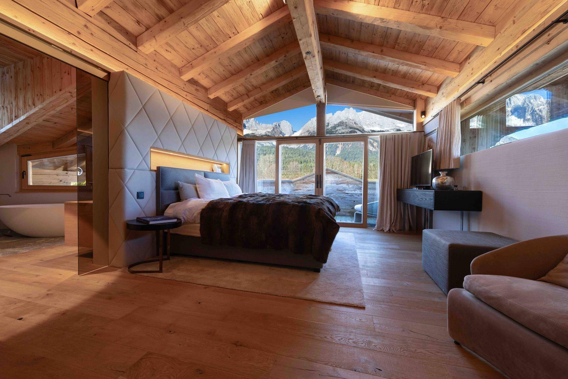 Luxuriöses Schlafzimmer im Dachgeschoss mit Bergblick, Holzbalkendecke und Badewanne.