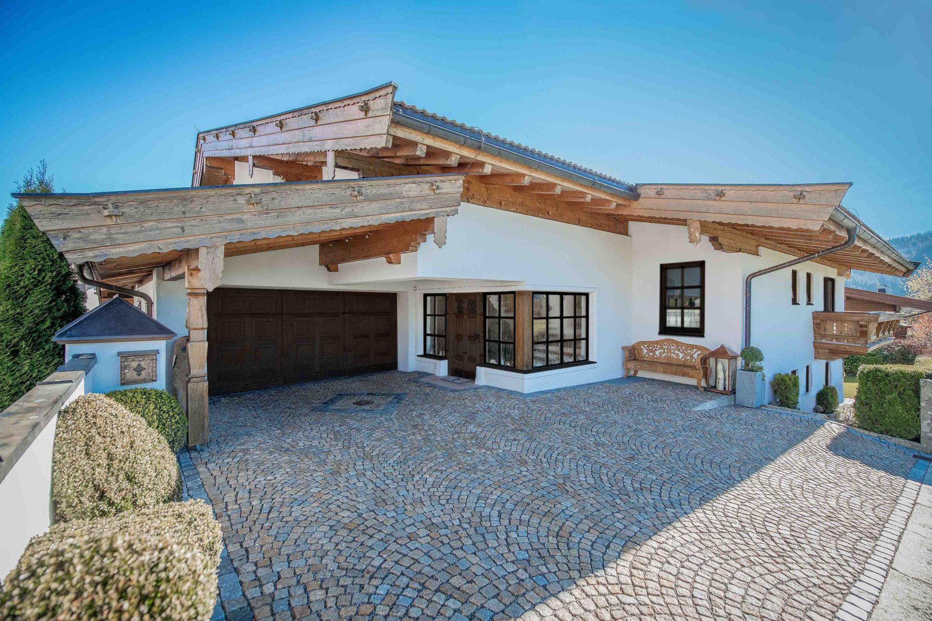 Traditionelles Haus im alpinen Stil mit gepflasterter Auffahrt und Doppelgarage.