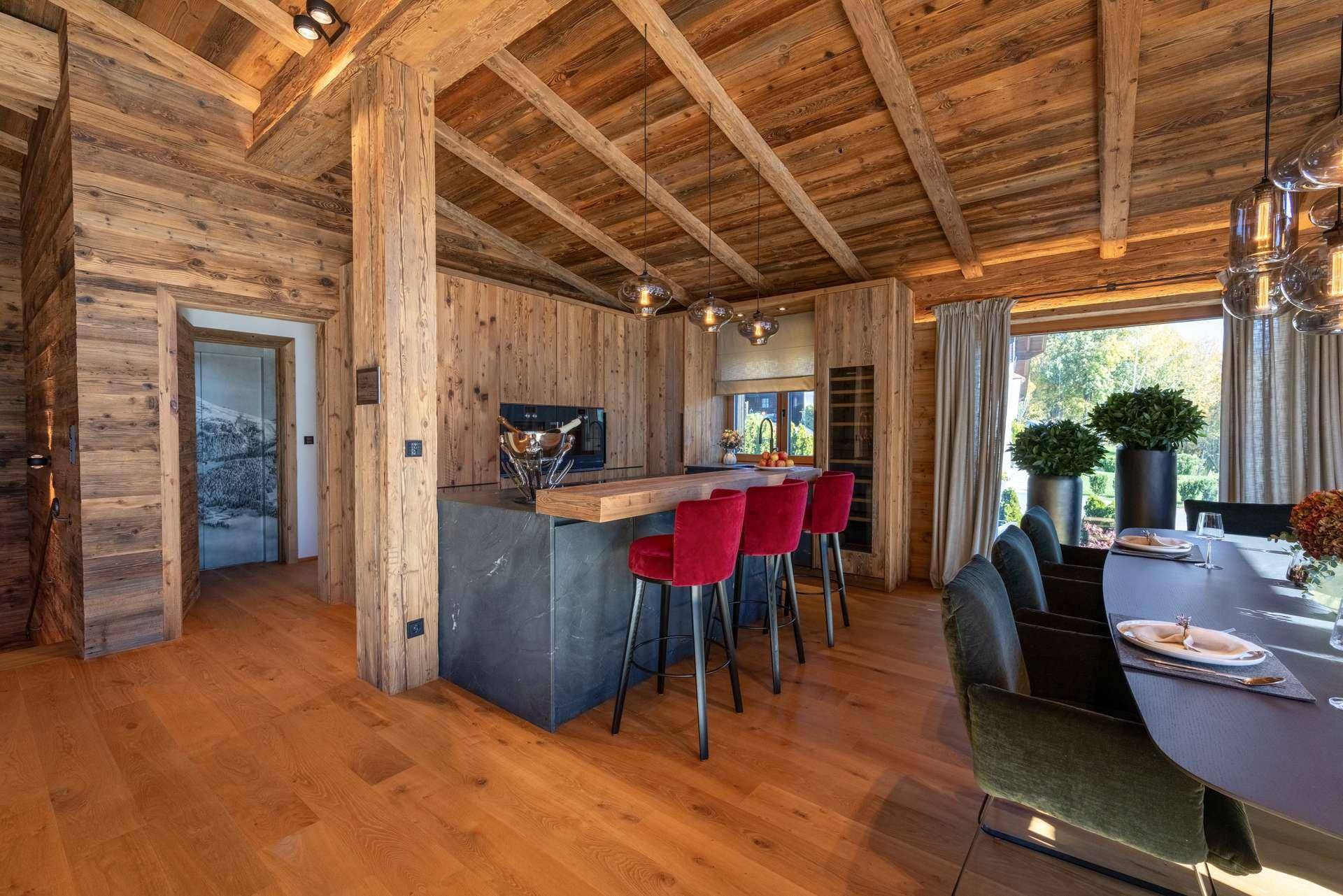 Offene Küche im Landhausstil mit Holzverkleidung, Kücheninsel und modernen Barhockern, angrenzend an den Essbereich.