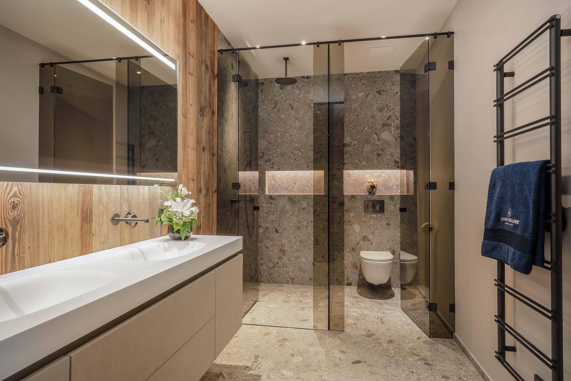Modernes Badezimmer mit Doppelwaschbecken, begehbarer Dusche und beheiztem Handtuchhalter.