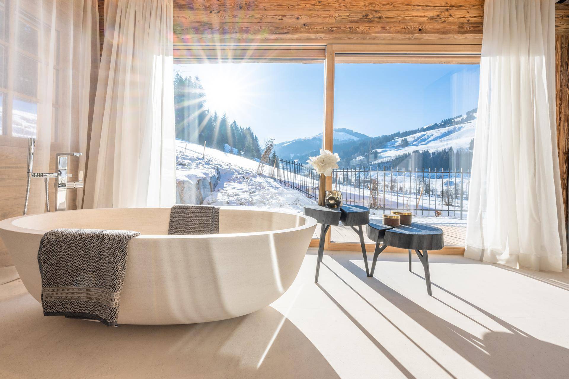 Luxuriöses Badezimmer mit freistehender Badewanne und atemberaubendem Blick auf die verschneiten Berge.
