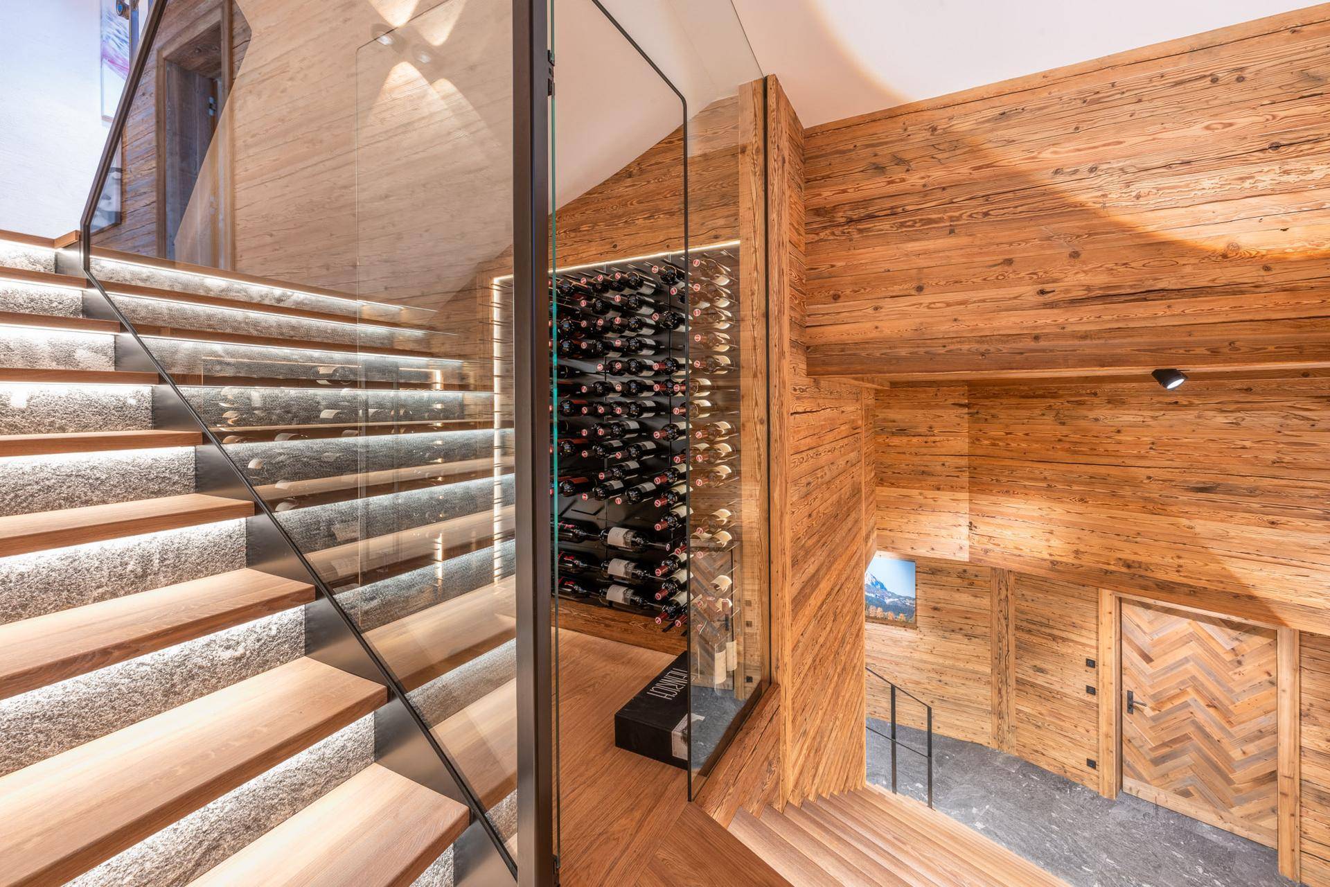 Elegante Treppe mit Glasgeländer und integriertem Weinkeller, umgeben von warmem Holz.