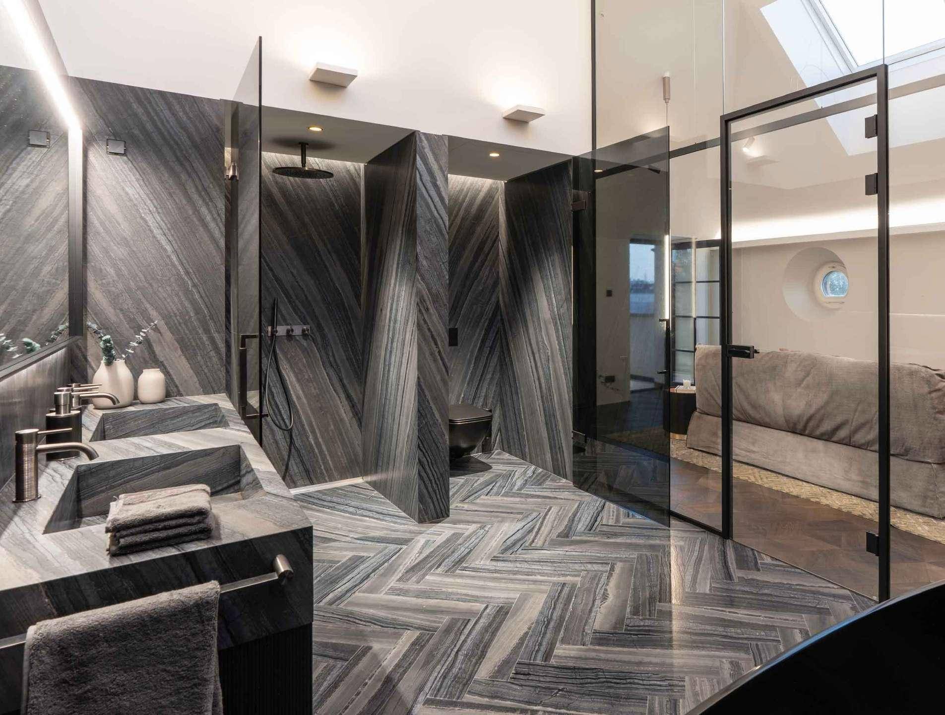 Luxuriöses Badezimmer mit doppelten Waschbecken, begehbarer Dusche und eleganten Steinfliesen.