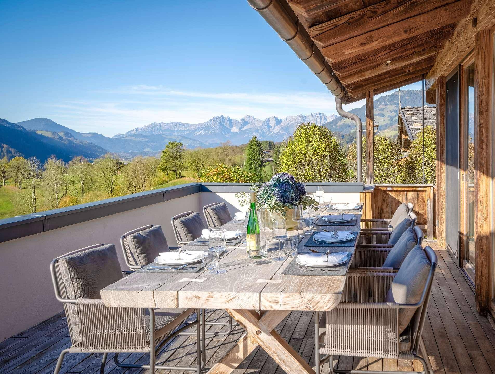 Große möblierte Terrasse mit Esstisch und Panoramablick auf die umliegende Berglandschaft.