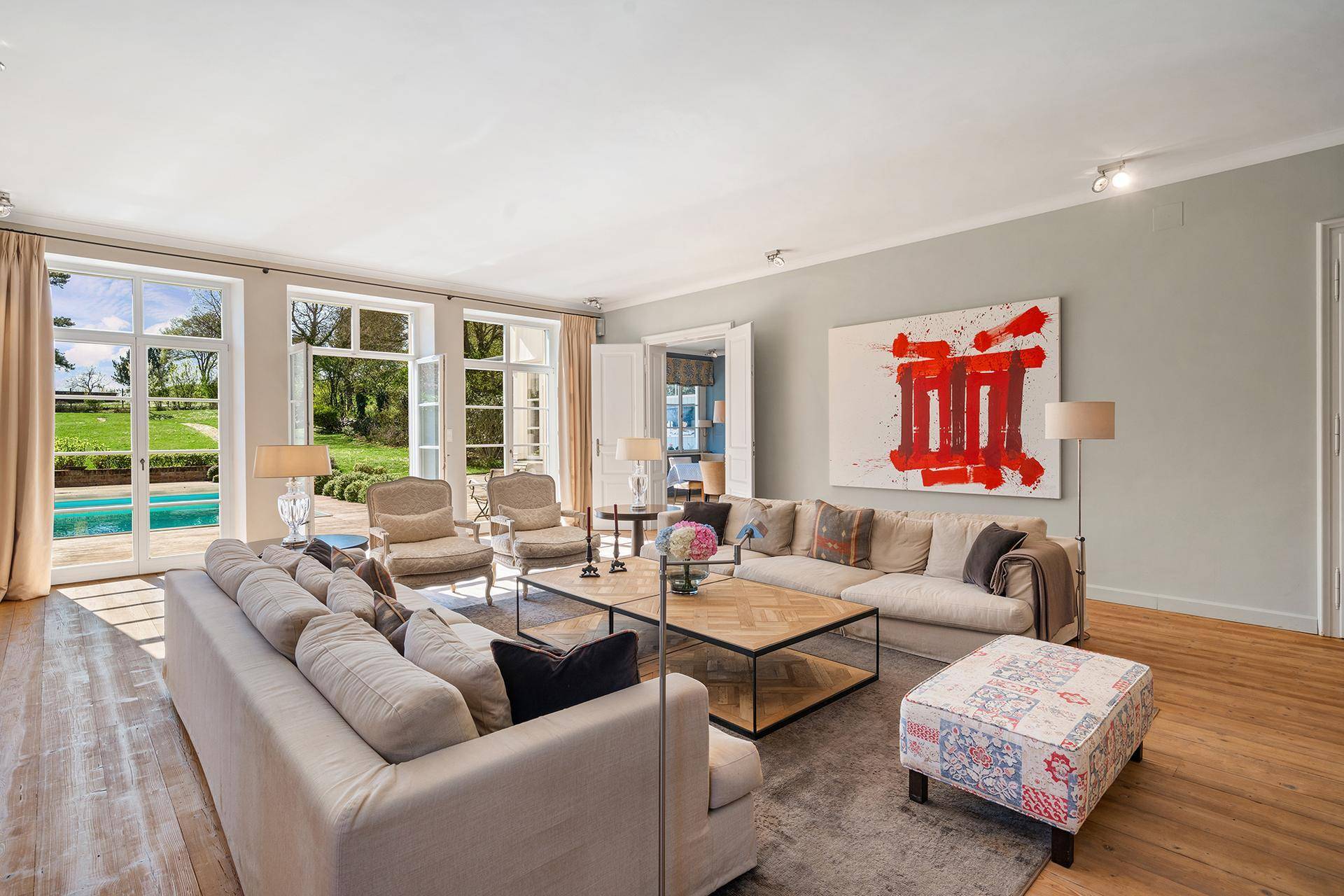 Geräumiges Wohnzimmer mit Holzboden, bequemen Sofas und direktem Zugang zur Poolterrasse.