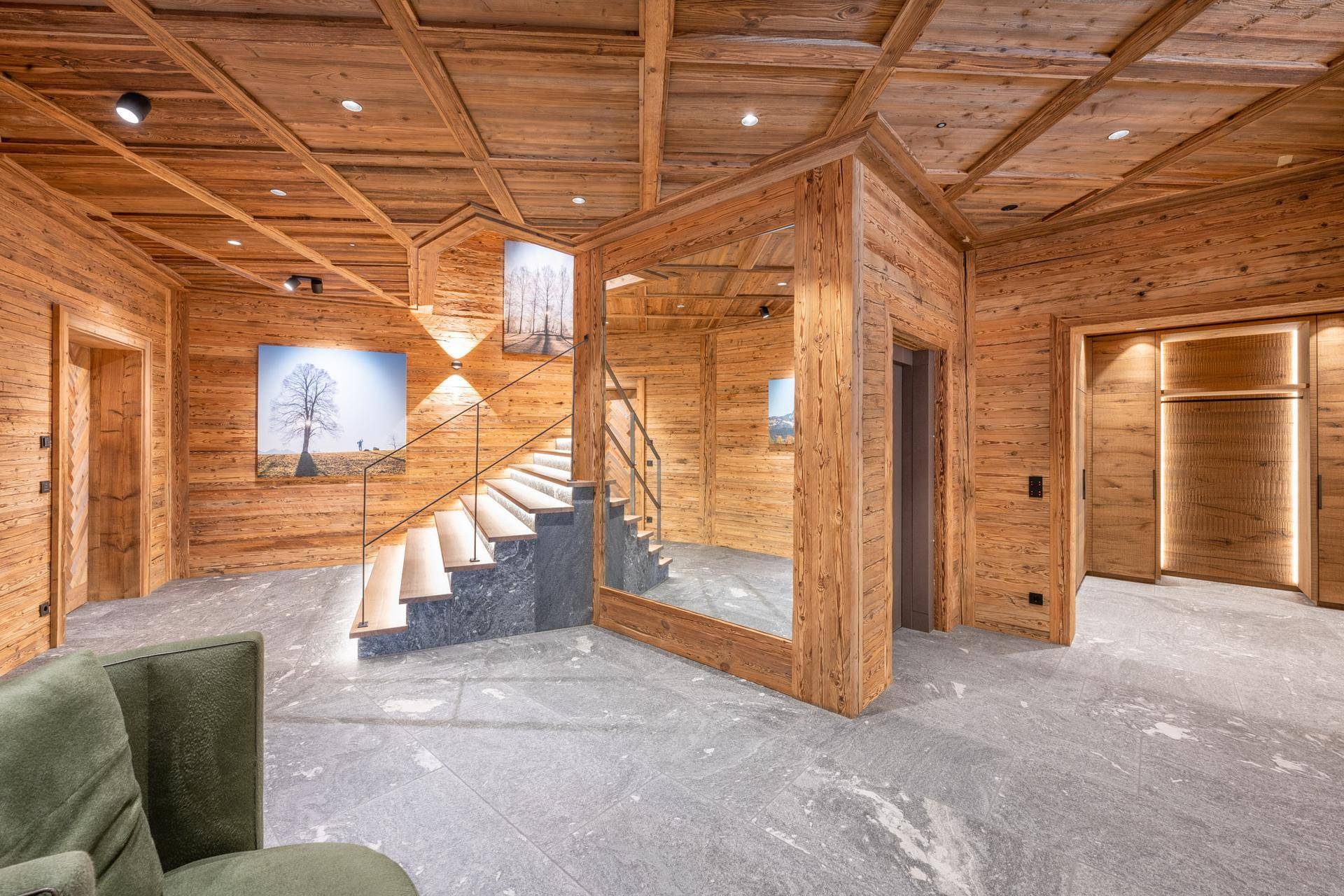 Geräumiger Flur mit Holzvertäfelung, Treppe, großem Spiegel und Zugang zum Aufzug.