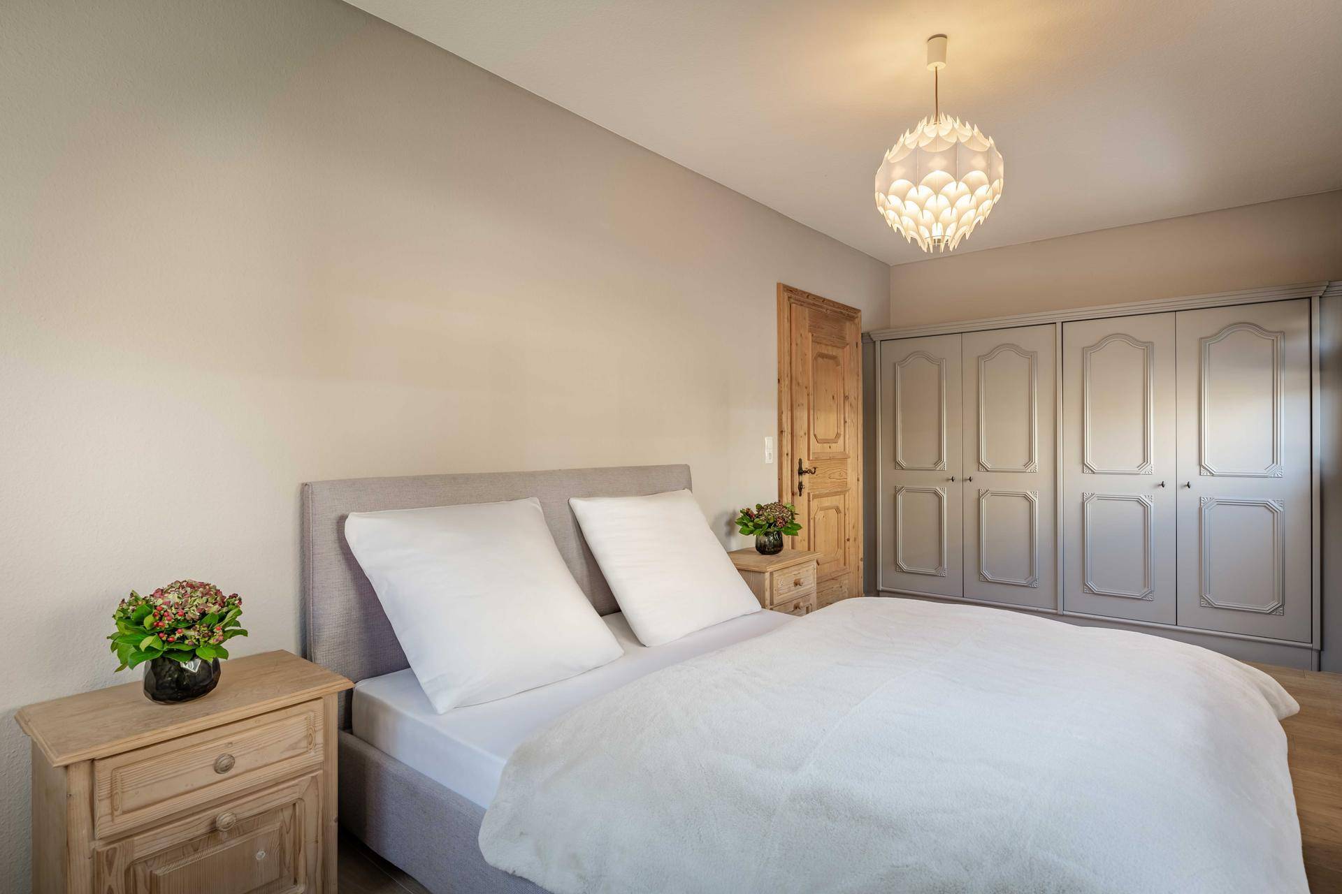 Helles Schlafzimmer mit großem Bett, Einbauschränken und Holztür.