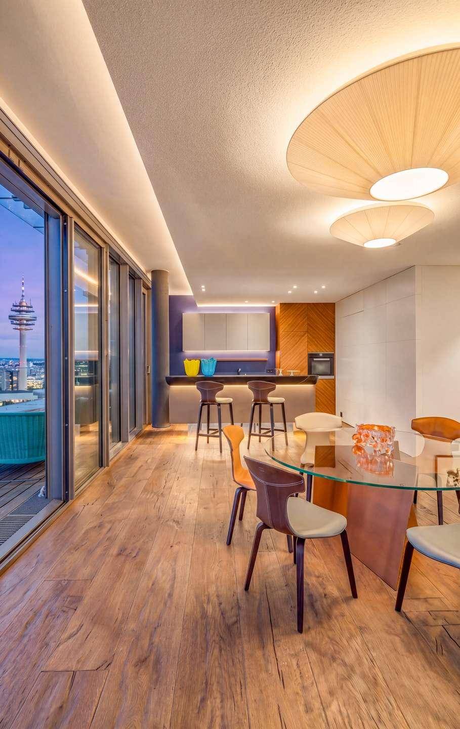 Moderner offener Wohn- und Essbereich mit integrierter Bar, Holzboden und Panoramafenstern mit Stadtblick.