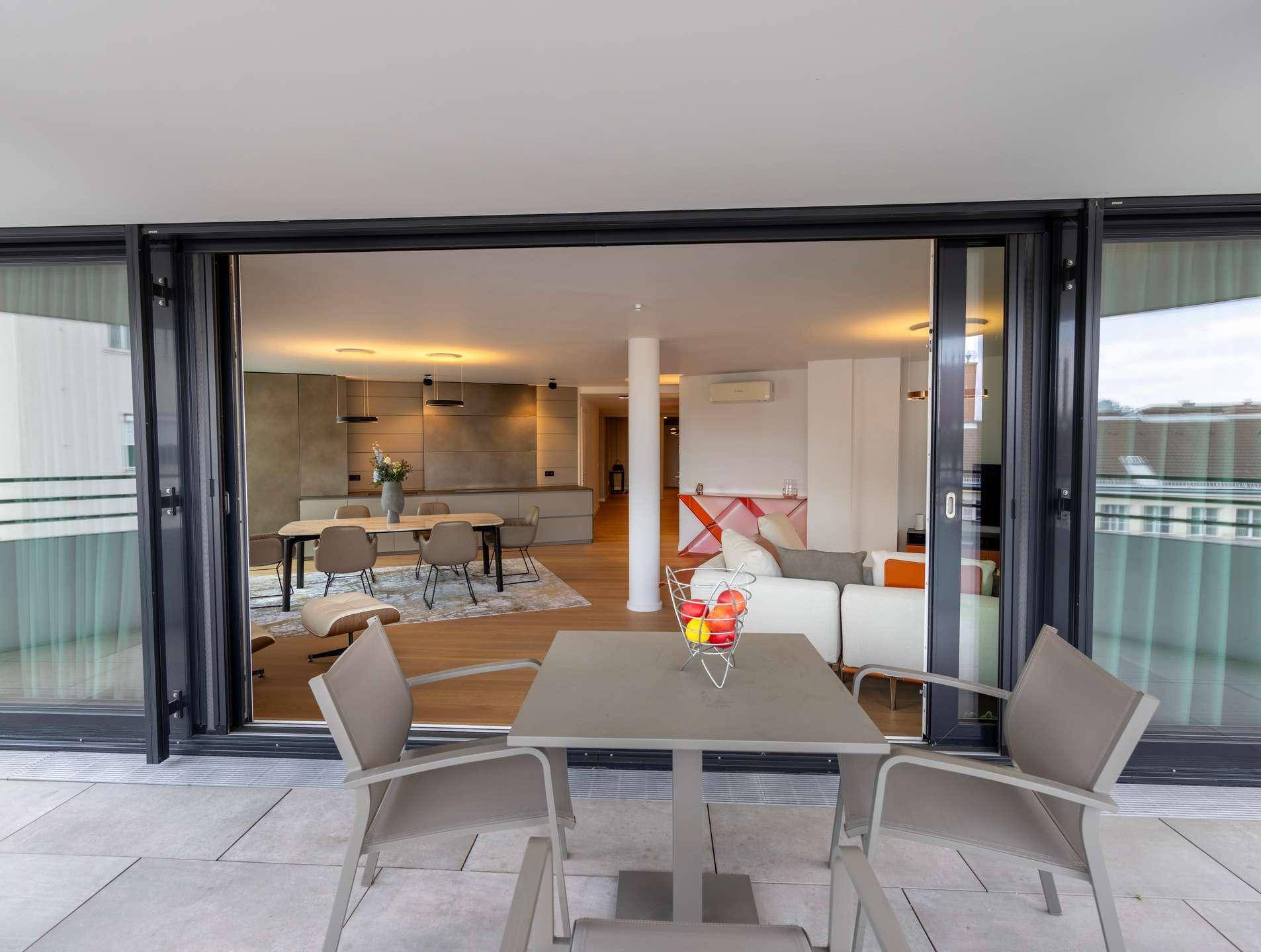 Geräumiger Balkon mit Sitzgelegenheiten und Blick in den offenen Wohnbereich der Wohnung.