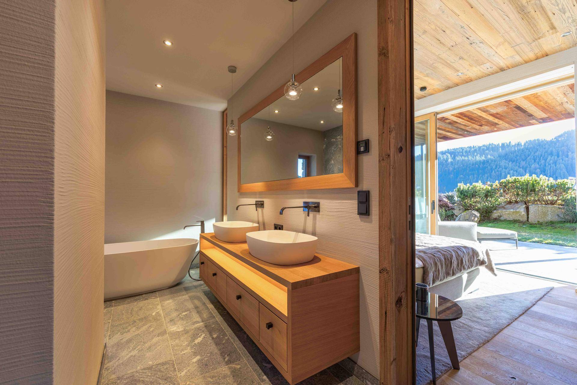 Modernes Badezimmer mit Doppelwaschbecken, freistehender Badewanne und Holzelementen.