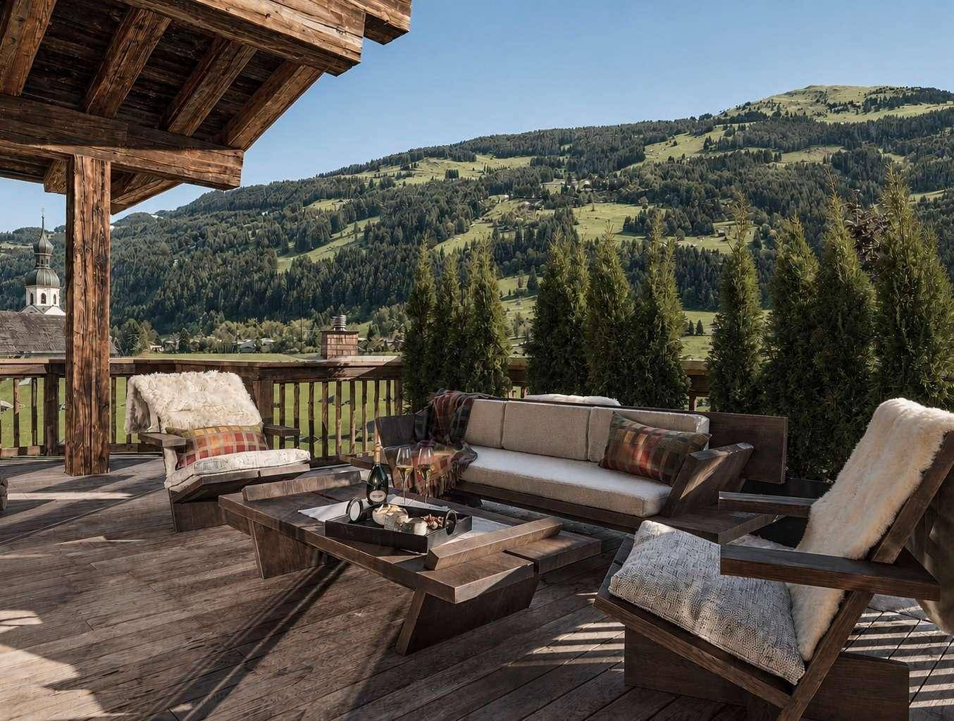 Sonnige Holzterrasse mit bequemen Sitzmöbeln und weitem Blick auf die umliegende Berglandschaft.