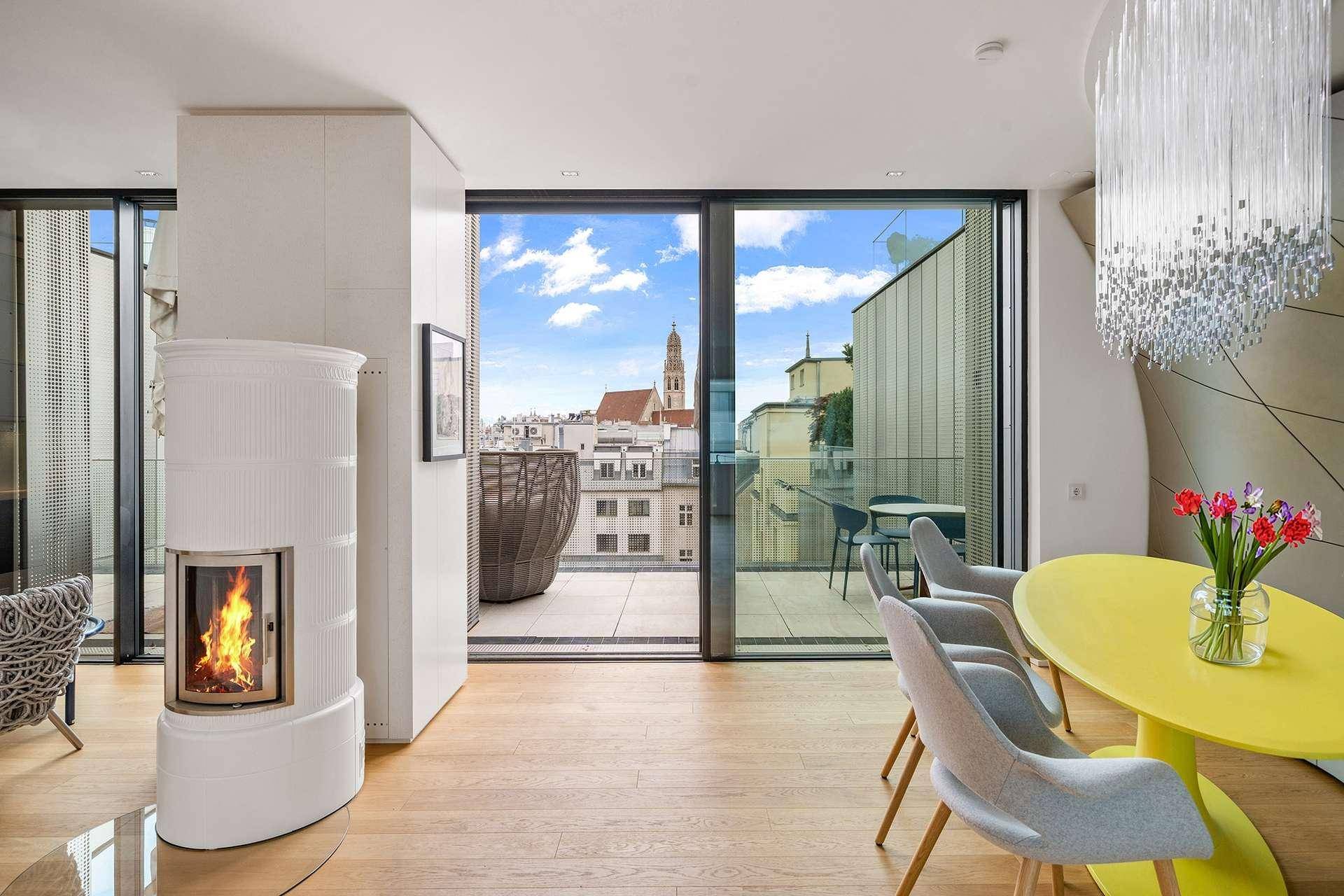 Lichtdurchfluteter Wohn-Essbereich mit Kaminofen, Holzboden und Zugang zur Dachterrasse mit Stadtblick.