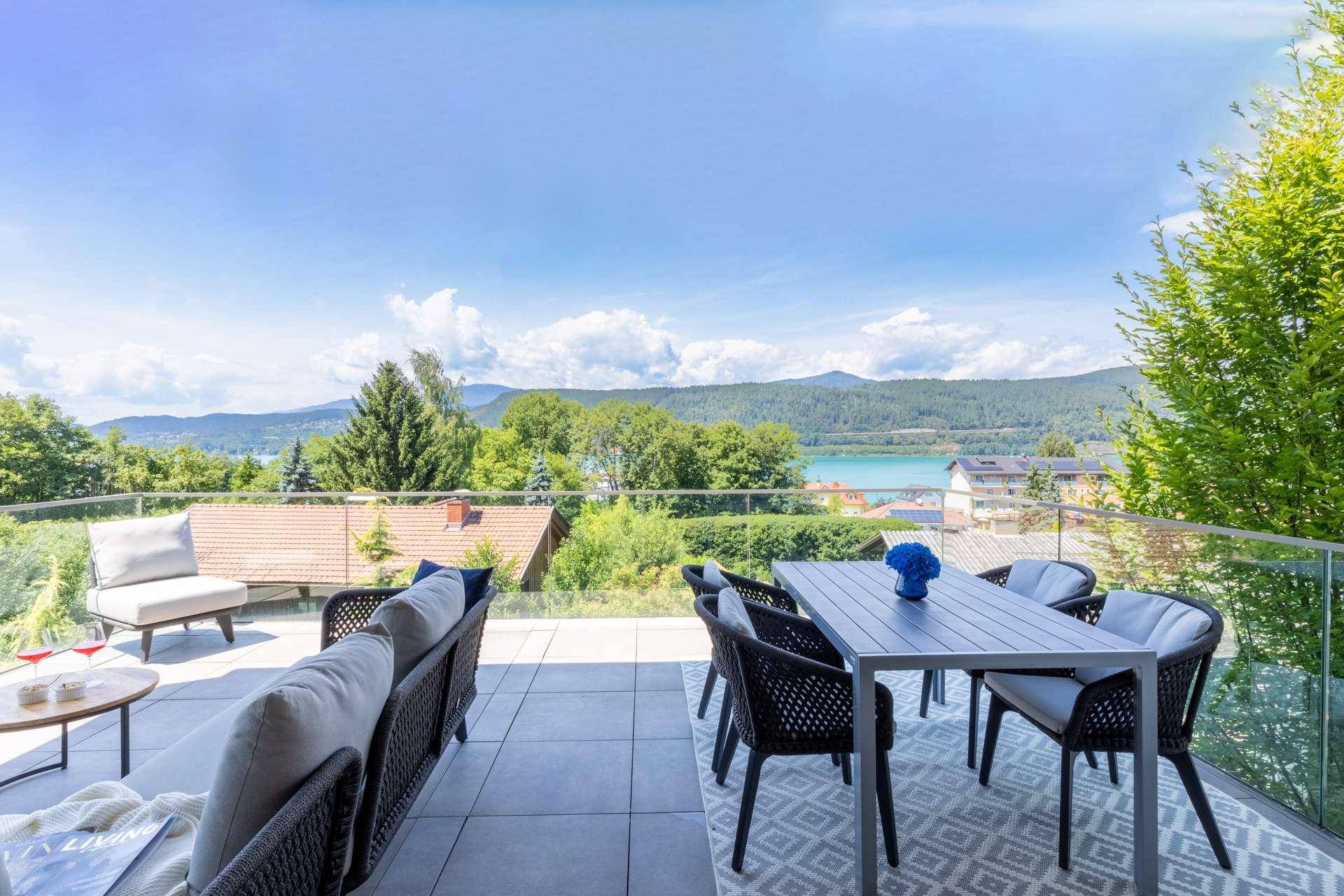 Große Sonnenterrasse mit modernen Gartenmöbeln und weitem Blick über den See und die Berge.