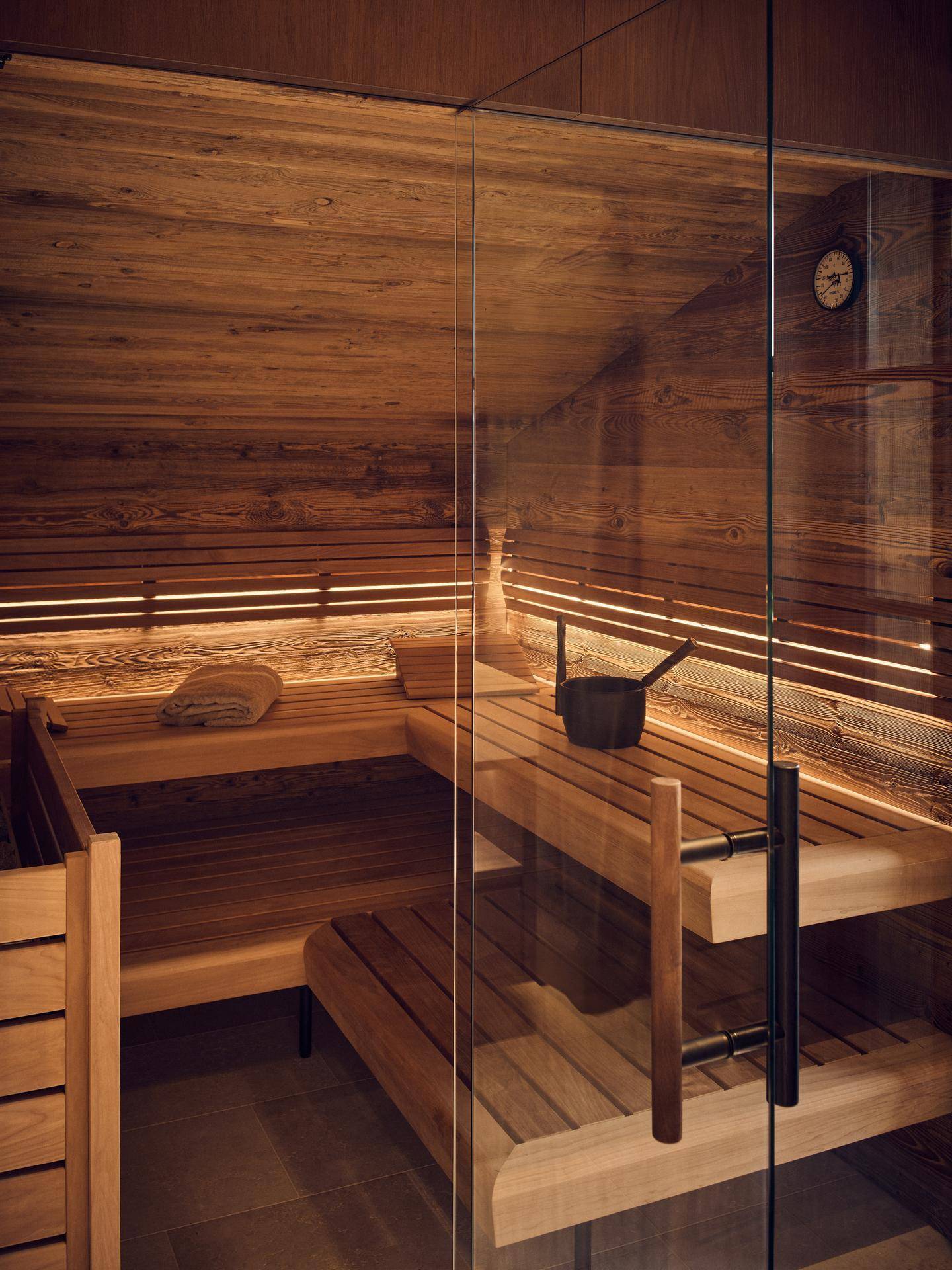 Moderne Holzsauna mit indirekter Beleuchtung und bequemen Sitzbänken.