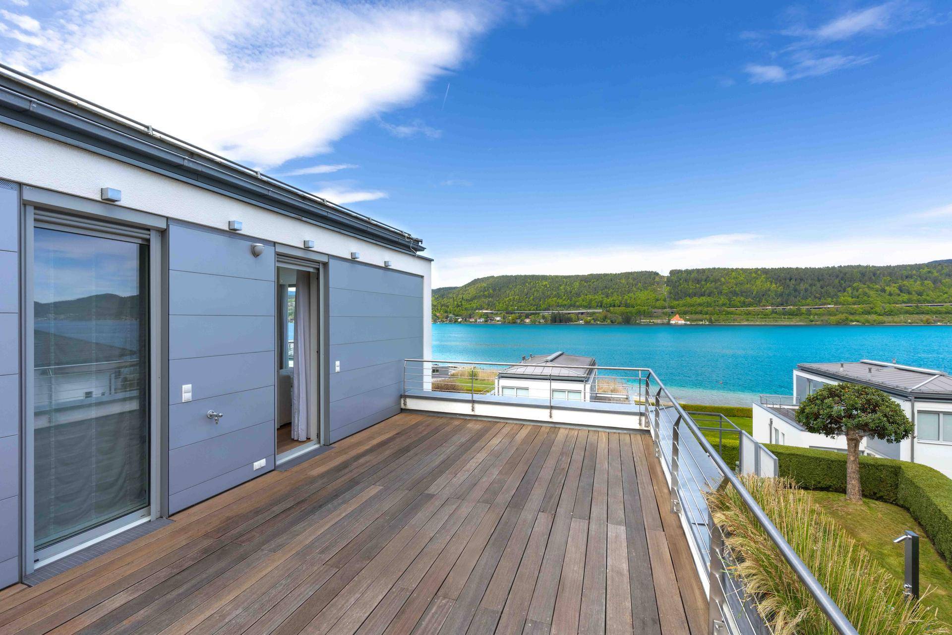 Geräumiger Balkon mit Holzboden und atemberaubendem Panoramablick auf den See und die Berge.