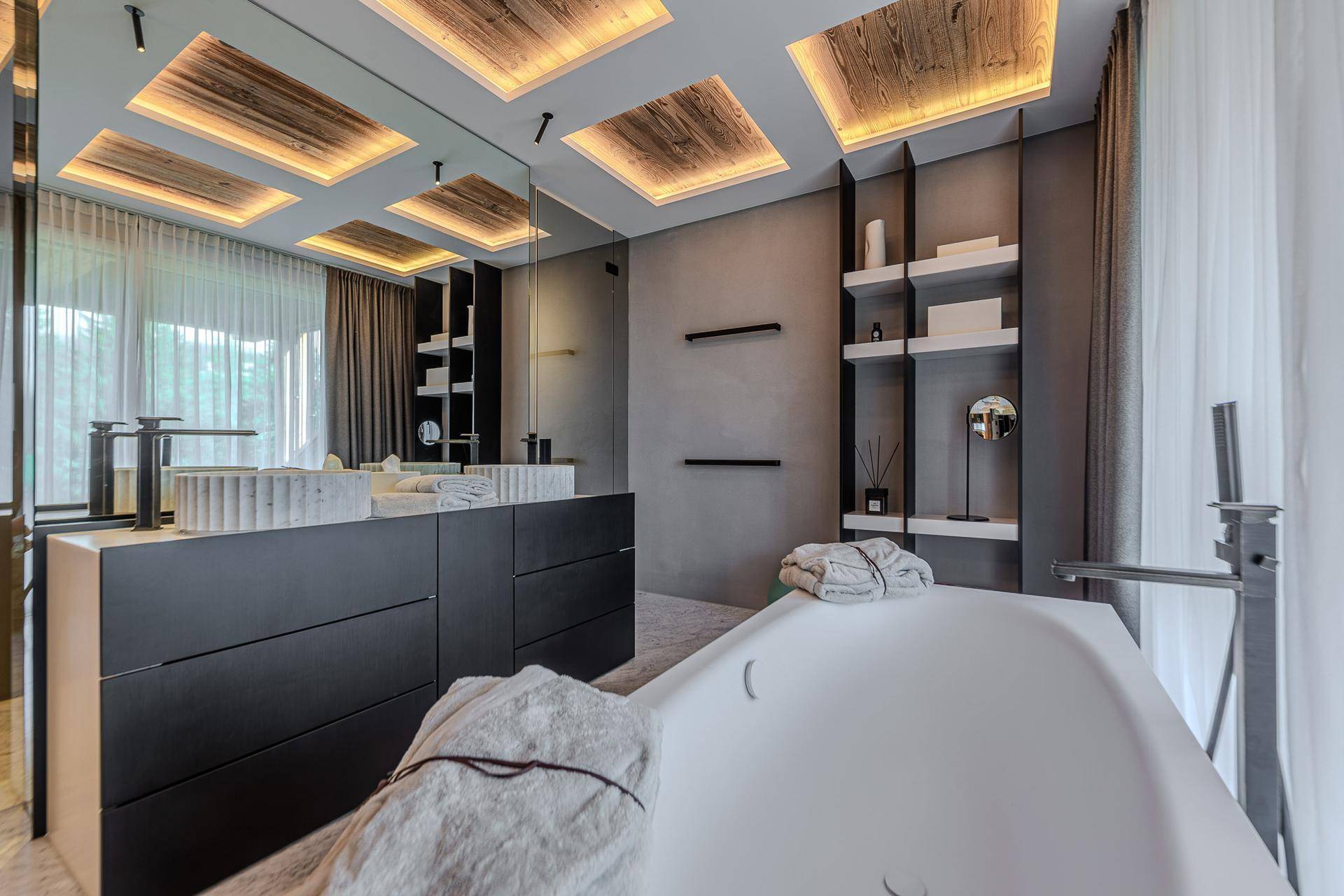 Modernes Badezimmer mit freistehender Badewanne, Doppelwaschbecken und stilvoller Beleuchtung.