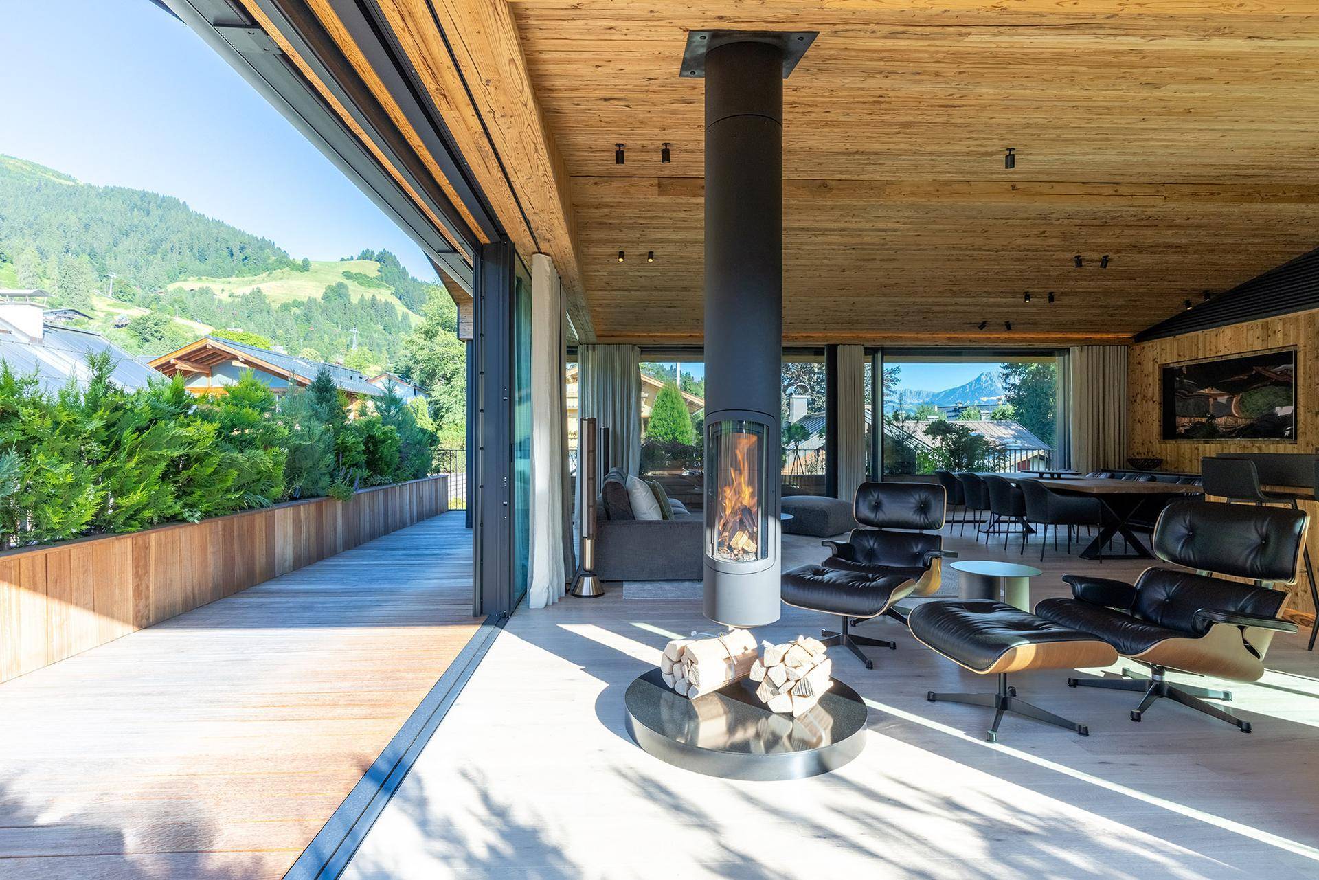 Geräumiger Wohn-Essbereich mit modernem Kamin, Holzelementen und Panoramablick auf die umliegenden Berge.