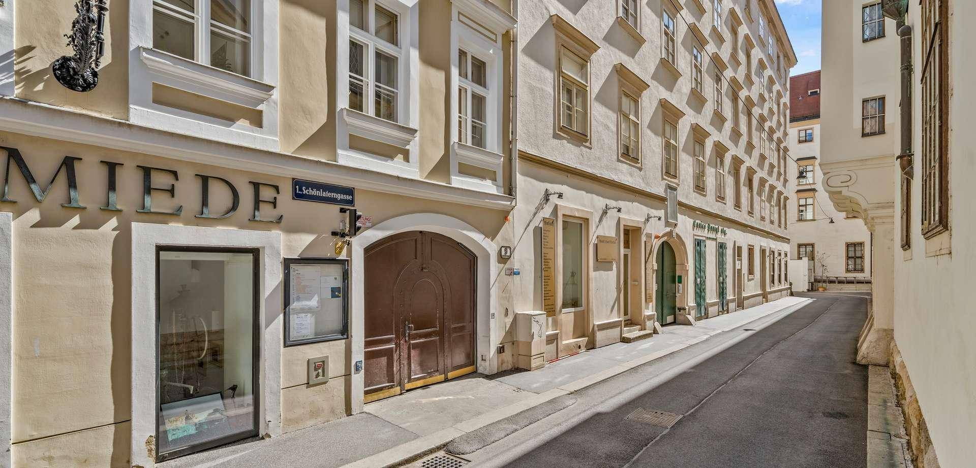 Historische Gebäudefassade mit Geschäften im Erdgeschoss und einer ruhigen Gasse.