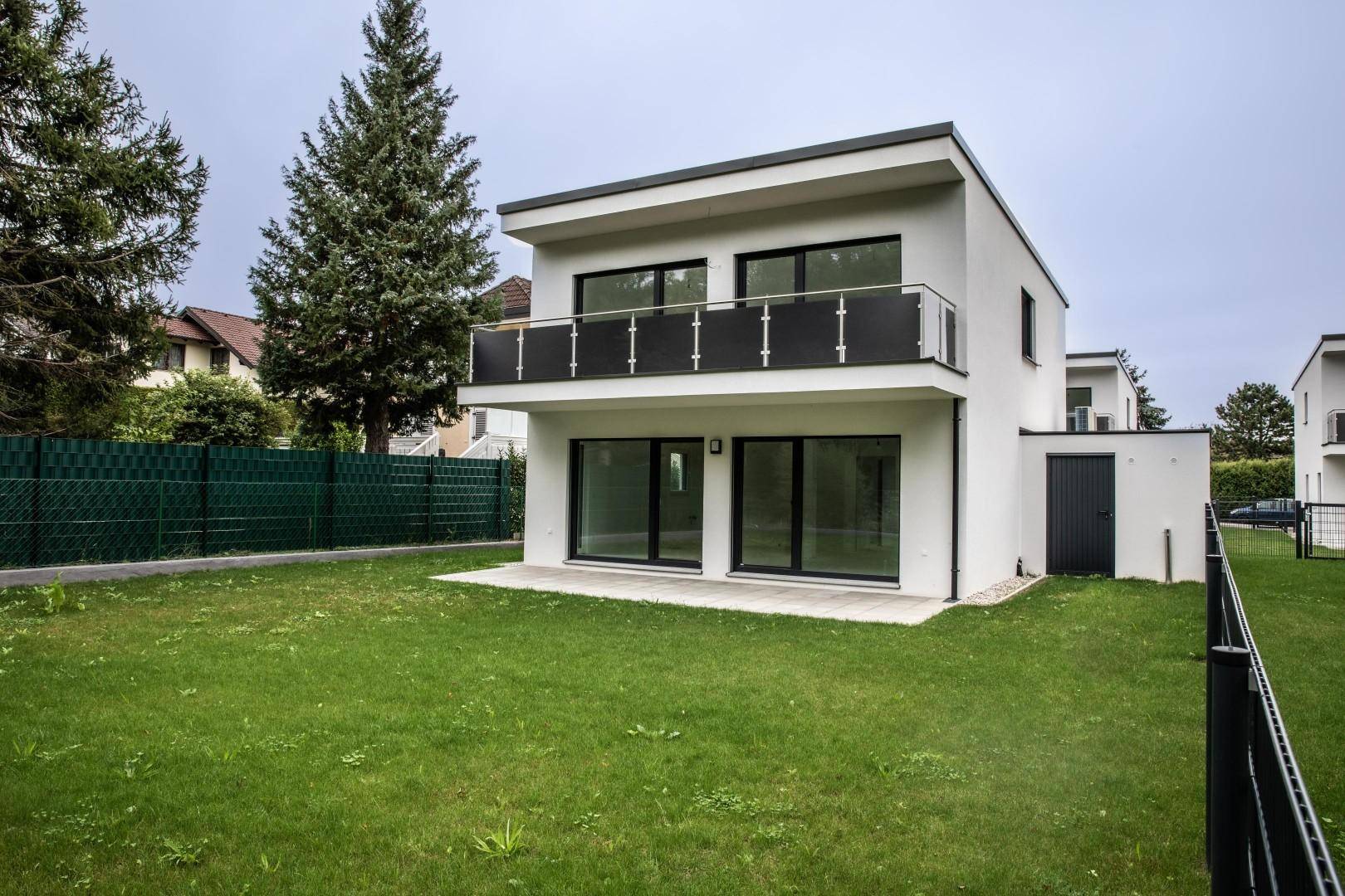 Einzelnes modernes Haus mit weißer Fassade, Balkon und großem Gartenbereich.
