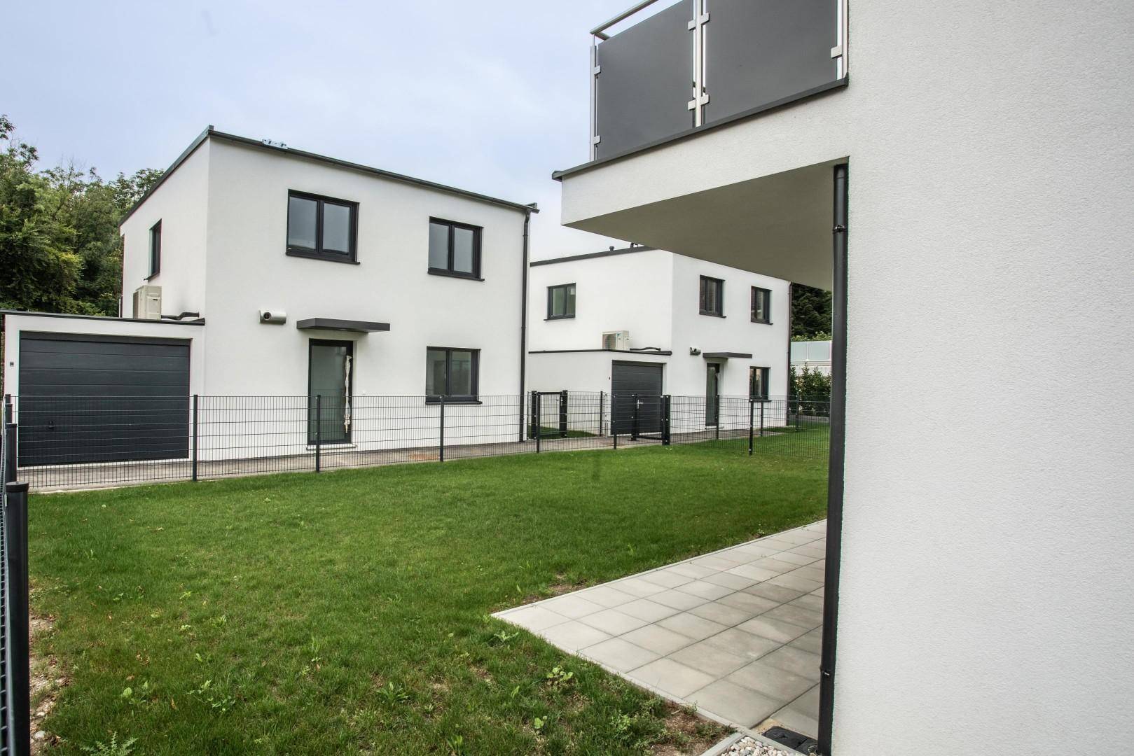 Blick auf den grünen Garten und die Terrasse eines modernen Reihenhauses.