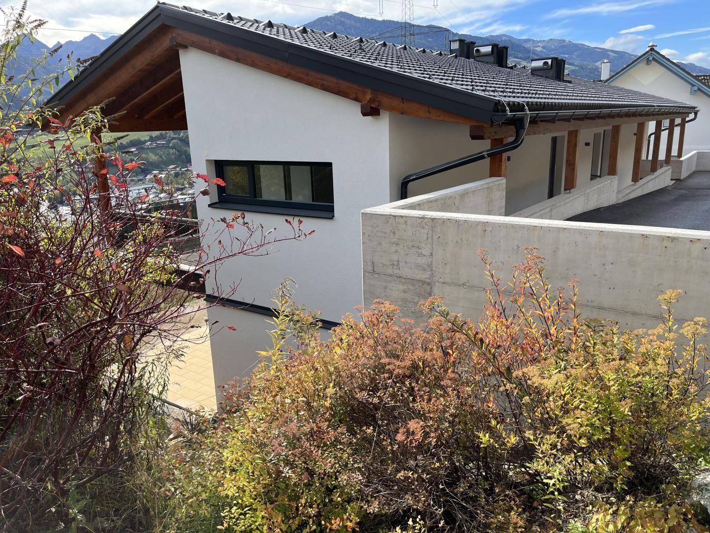 Ansicht eines modernen Gebäudes mit weißer Fassade, Betonmauer und Blick auf die umliegende Natur.
