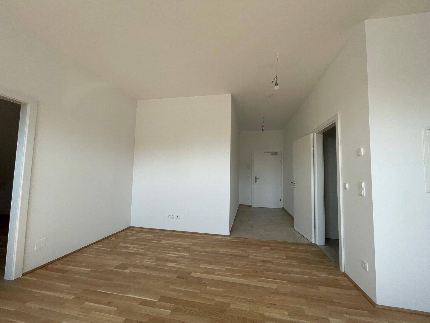 Heller Eingangsbereich mit Holzboden, der zu weiteren Zimmern der Wohnung führt.
