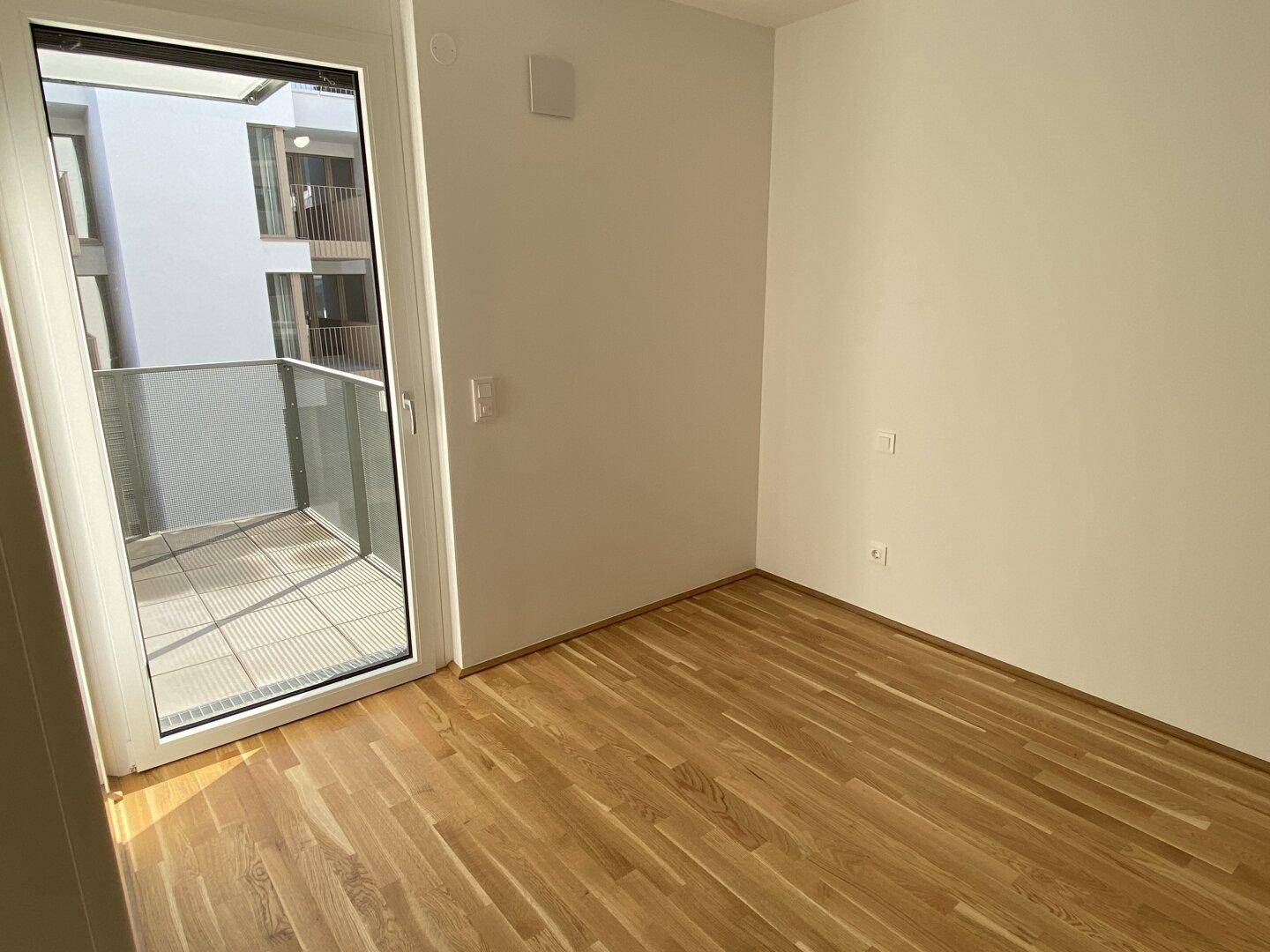 Helles Schlafzimmer mit Parkettboden und direktem Zugang zu einem privaten Balkon.