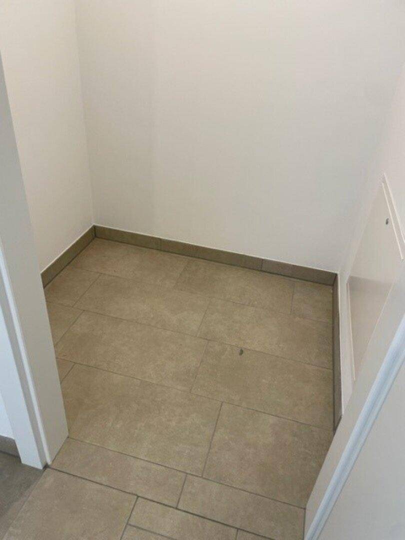 Kleiner Abstellraum mit beigefarbenen Fliesen, ideal für zusätzlichen Stauraum.