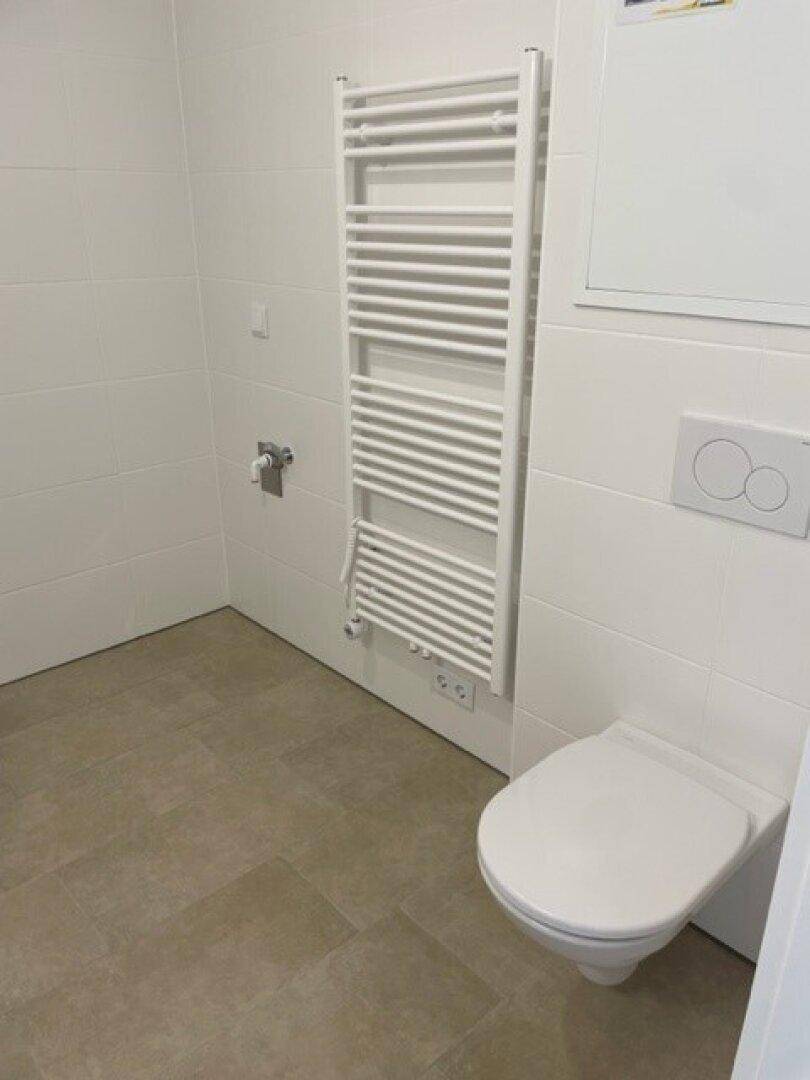Separates WC mit wandmontierter Toilette und beheiztem Handtuchhalter.