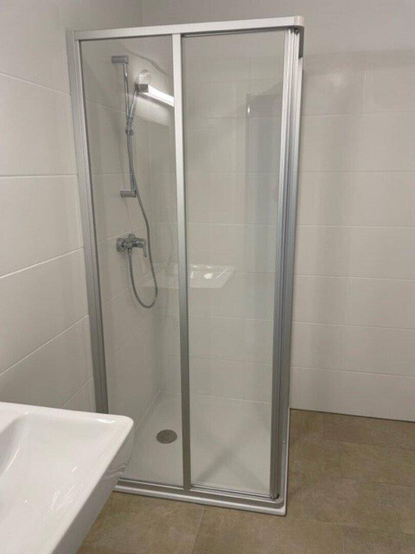 Duschkabine mit Glaswänden und moderner Armatur in einem hellen Badezimmer.