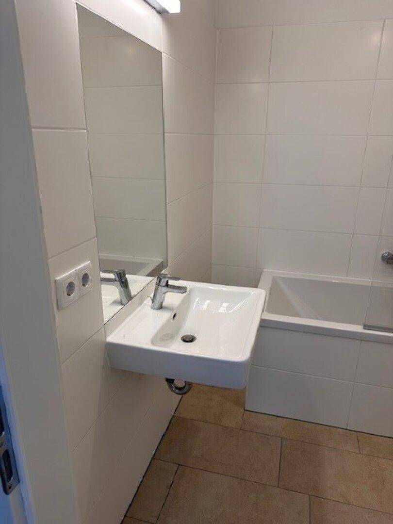Modernes Badezimmer mit Waschbecken, großem Spiegel und Badewanne.