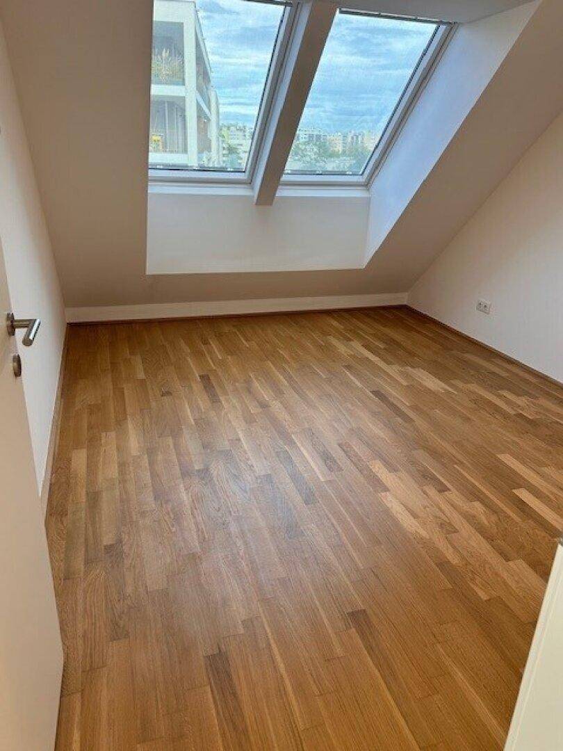 Helles Schlafzimmer im Dachgeschoss mit schrägen Wänden und großen Dachfenstern.