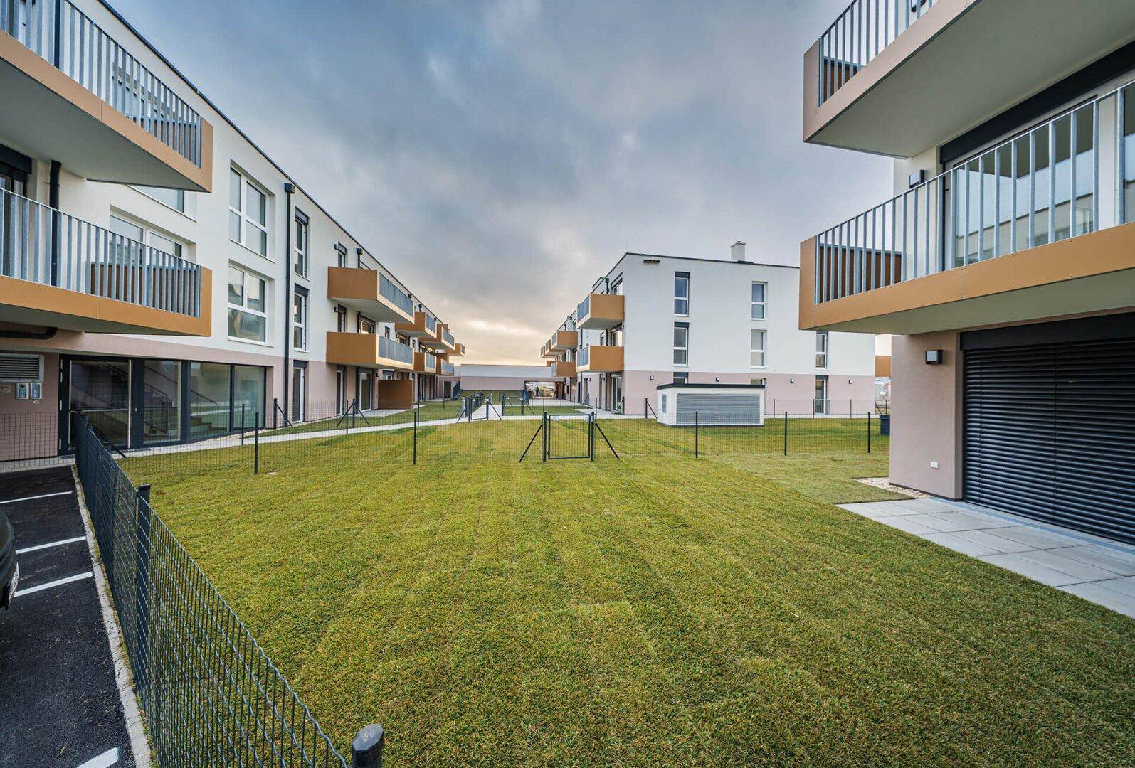 Innenhofansicht der modernen Wohngebäude mit Rasenflächen und privaten Terrassen im Erdgeschoss.