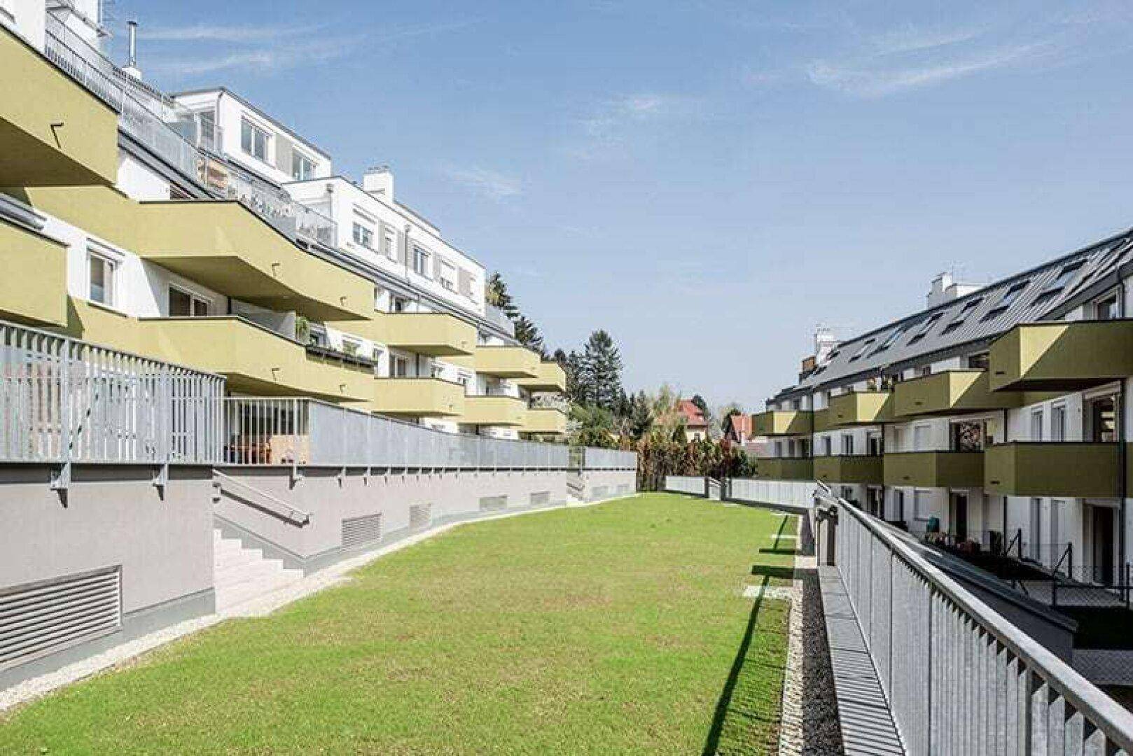 Grünfläche zwischen modernen Wohngebäuden mit Balkonen und Terrassen.