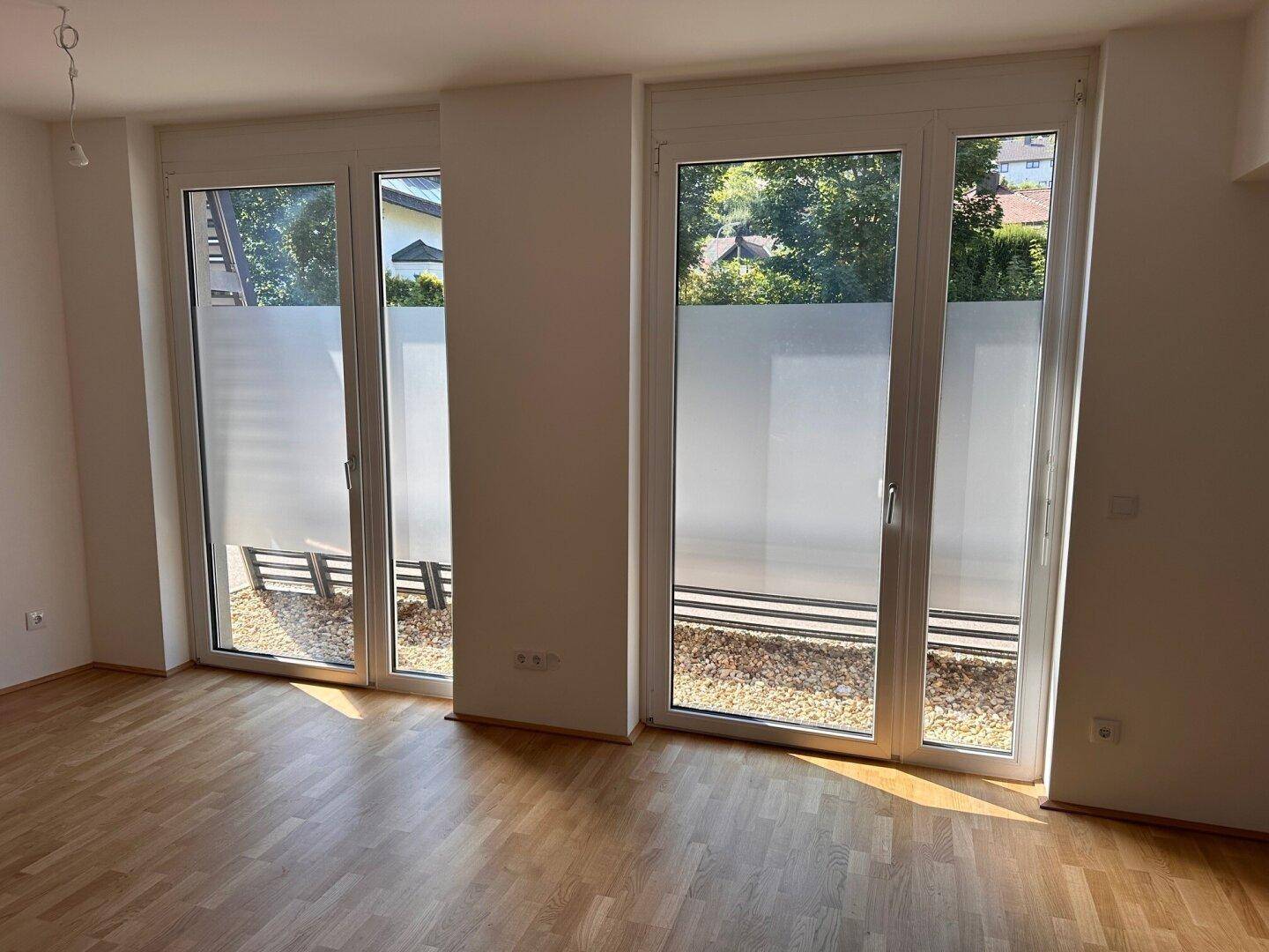 Große Fenstertüren im Wohnzimmer bieten Zugang zum Außenbereich mit Kies.