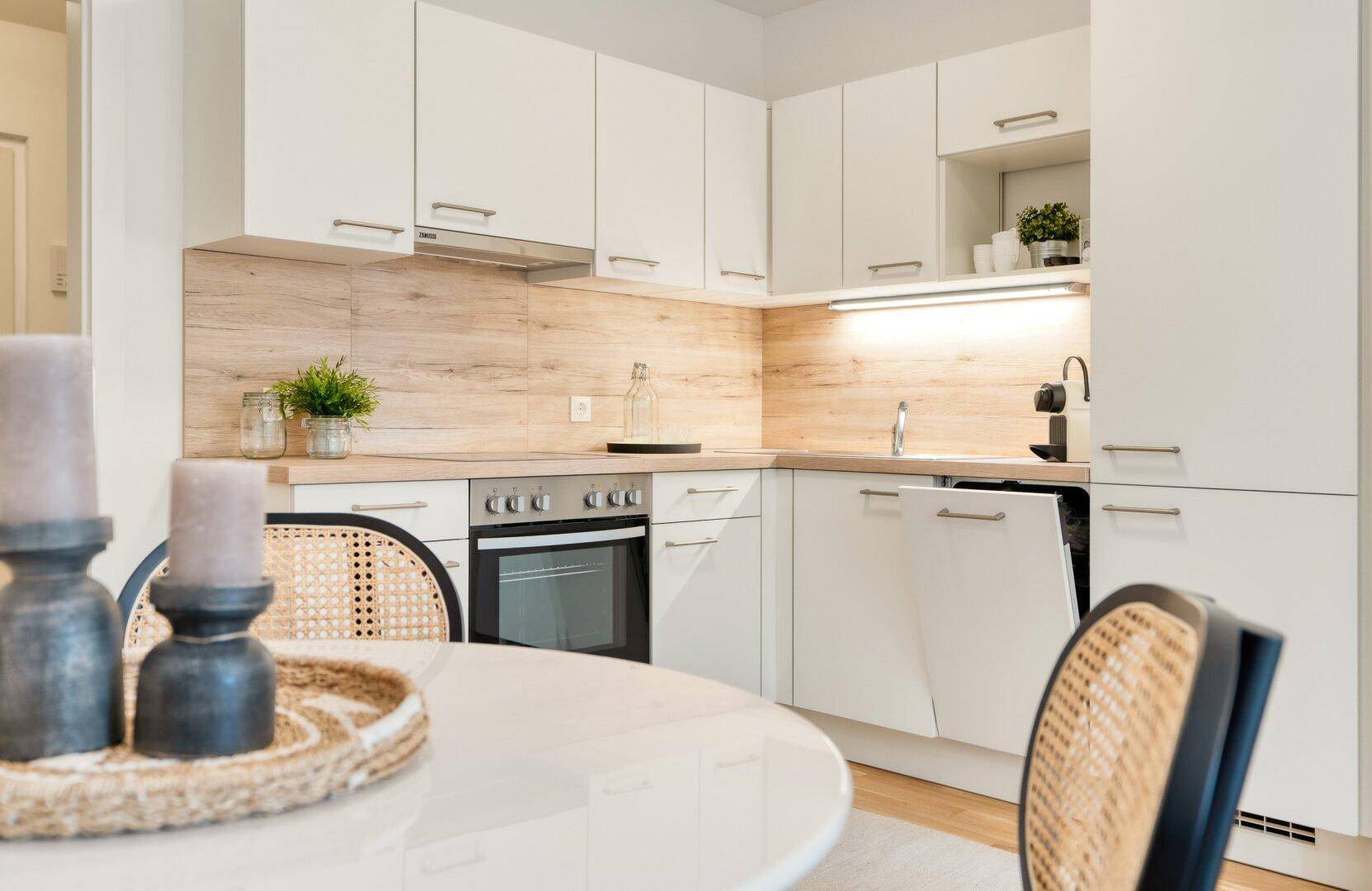Moderne Einbauküche in Weiß mit Holzakzenten, ausgestattet mit Geschirrspüler und Backofen.