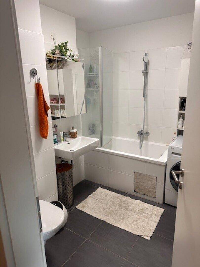 Modernes Badezimmer mit Badewanne, Dusche, Waschbecken und Waschmaschine.