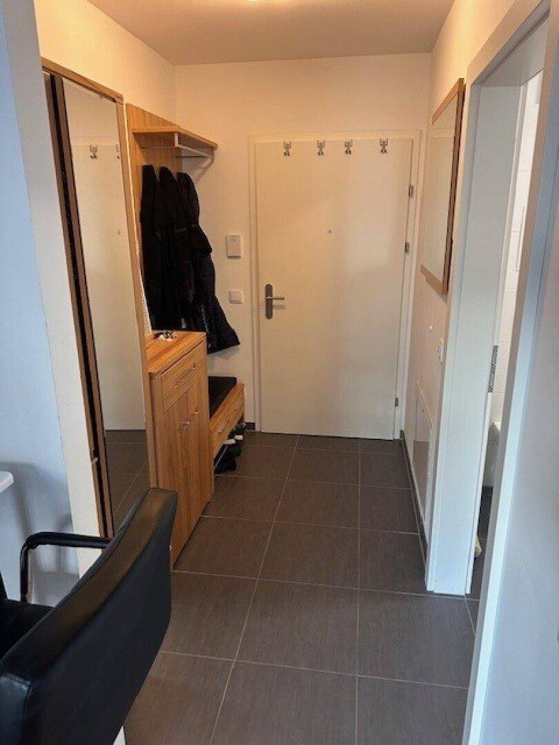 Eingangsbereich mit Fliesenboden, Garderobe und Spiegeln.