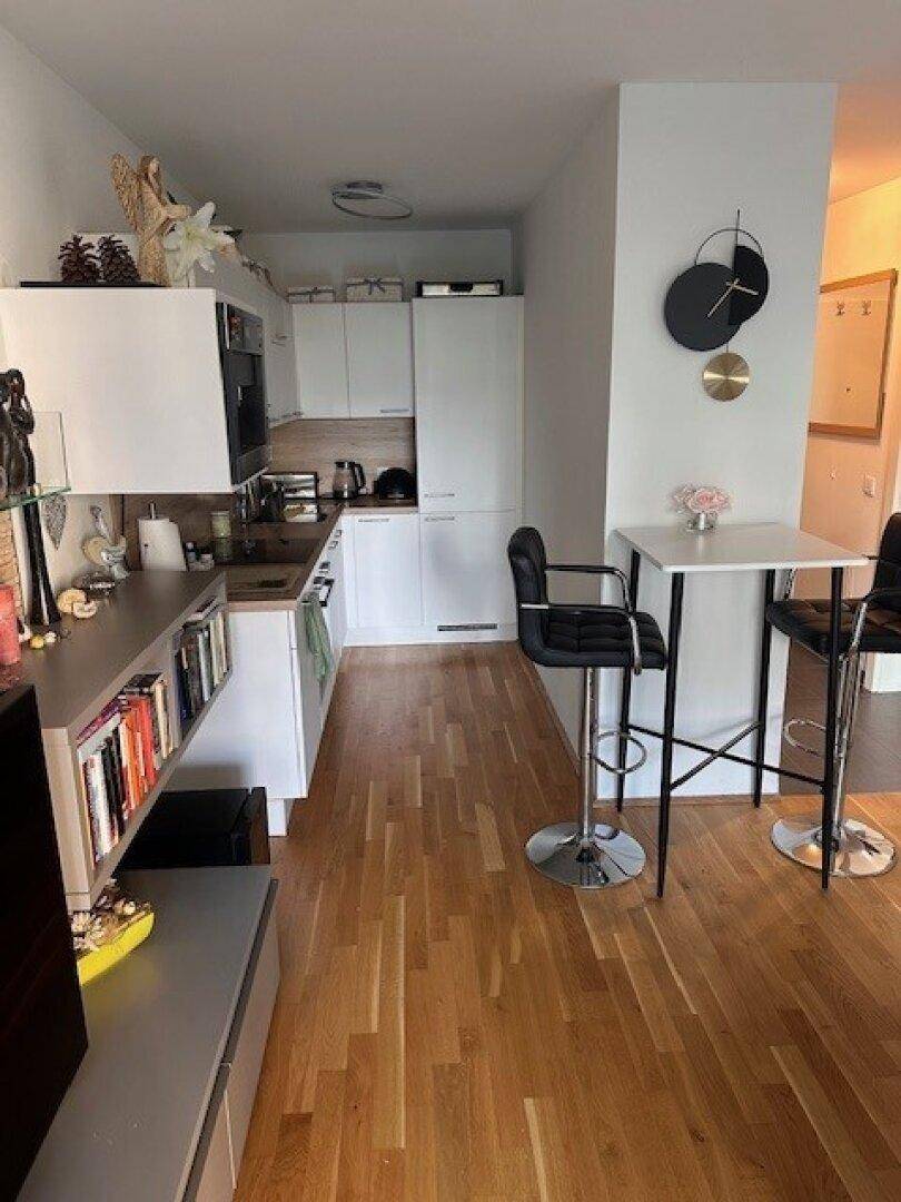 Kleine, moderne Küche mit weißen Schränken, Holzboden und Frühstücksbar.