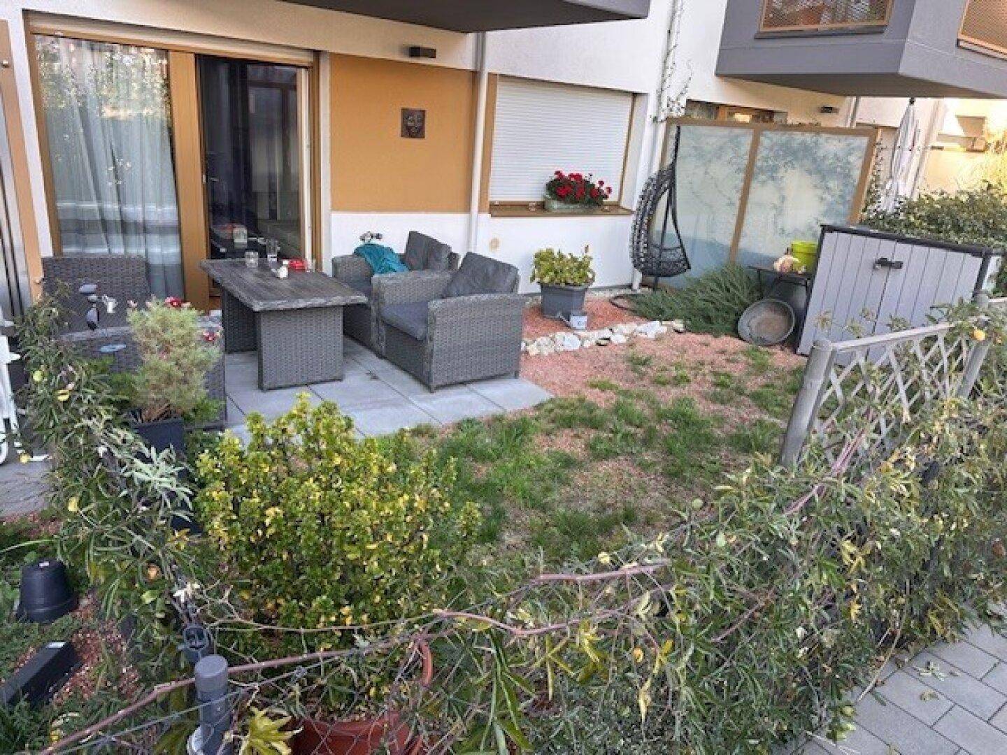 Terrasse mit Gartenmöbeln und angrenzendem kleinen Gartenbereich.