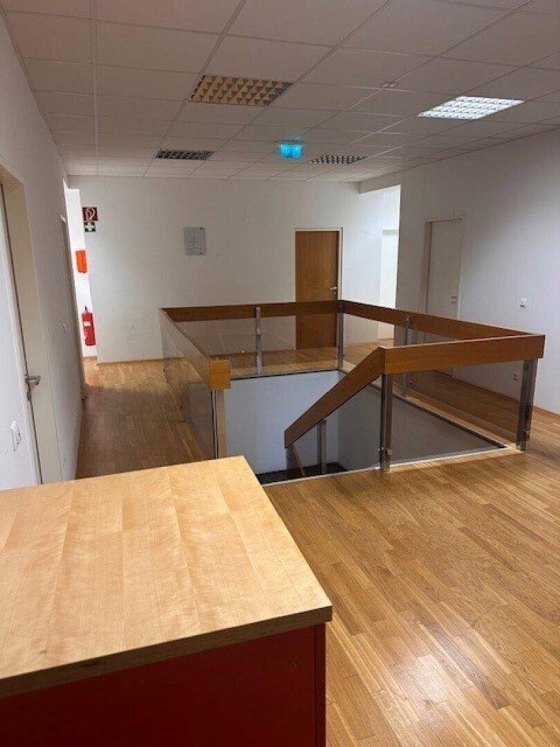 Heller Flur im Obergeschoss mit Holzparkett und moderner Glasbrüstung.