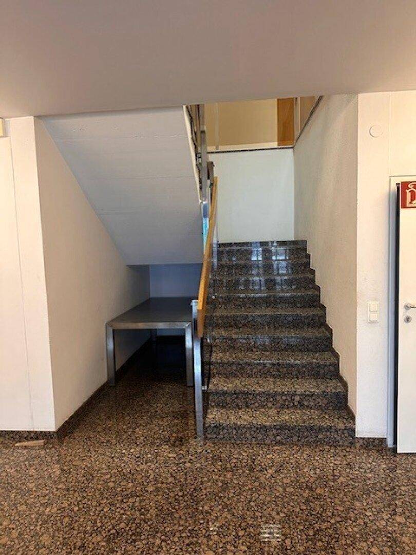 Treppenhaus mit Terrazzoboden und einer Treppe mit dunklen Granitstufen.
