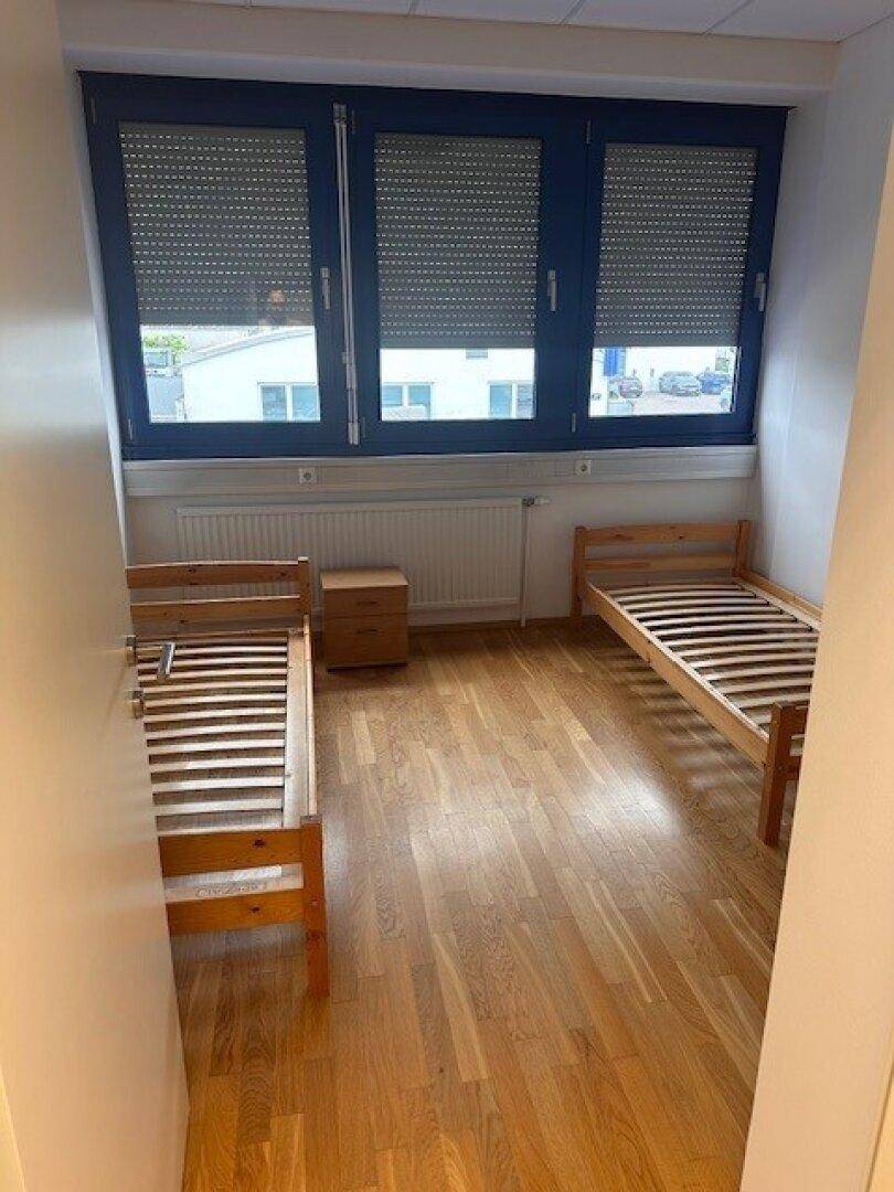 Schlafzimmer mit zwei Einzelbetten, Nachttisch und Fenstern mit Rollläden.