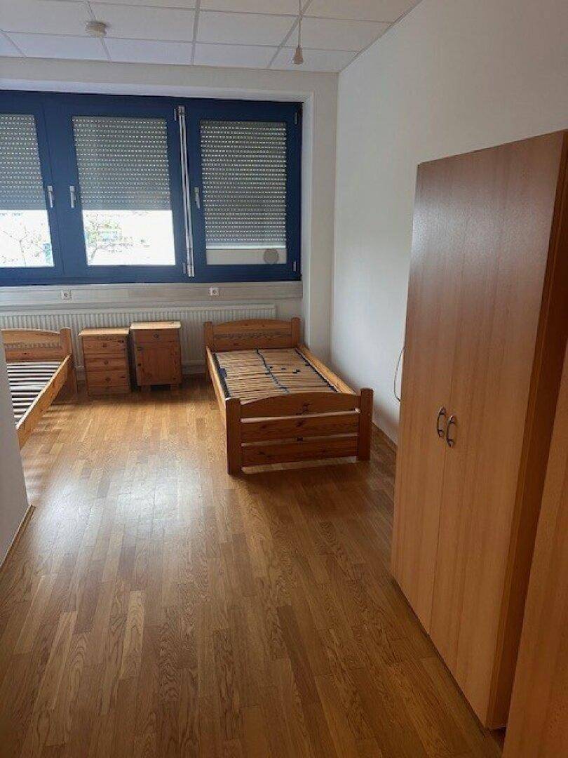Schlafzimmer mit zwei Einzelbetten, Nachttischen und einem Kleiderschrank.