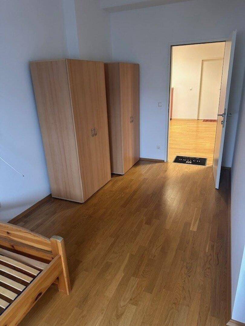 Schlafzimmer mit zwei Holzschränken und Blick in den Flur.