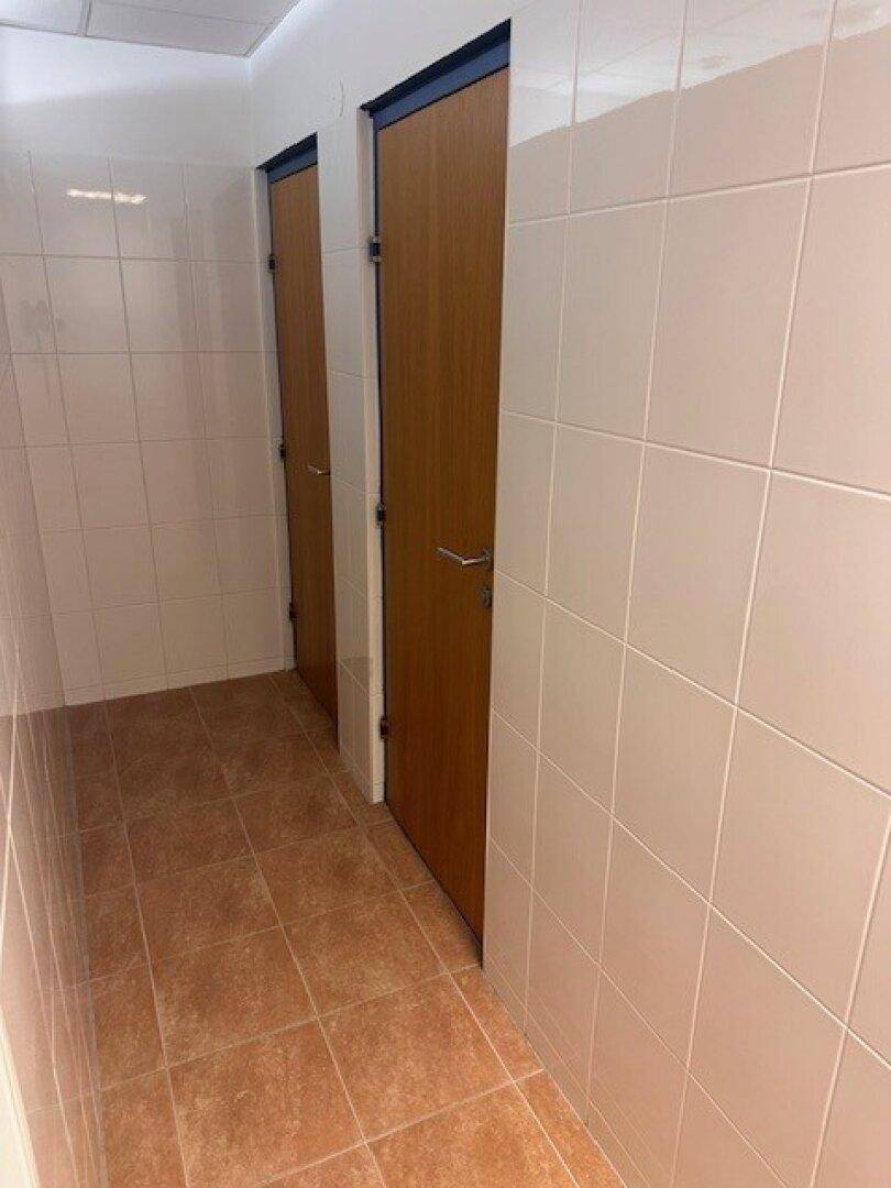 Toilettenbereich mit zwei Holztüren und weißen Fliesenwänden.